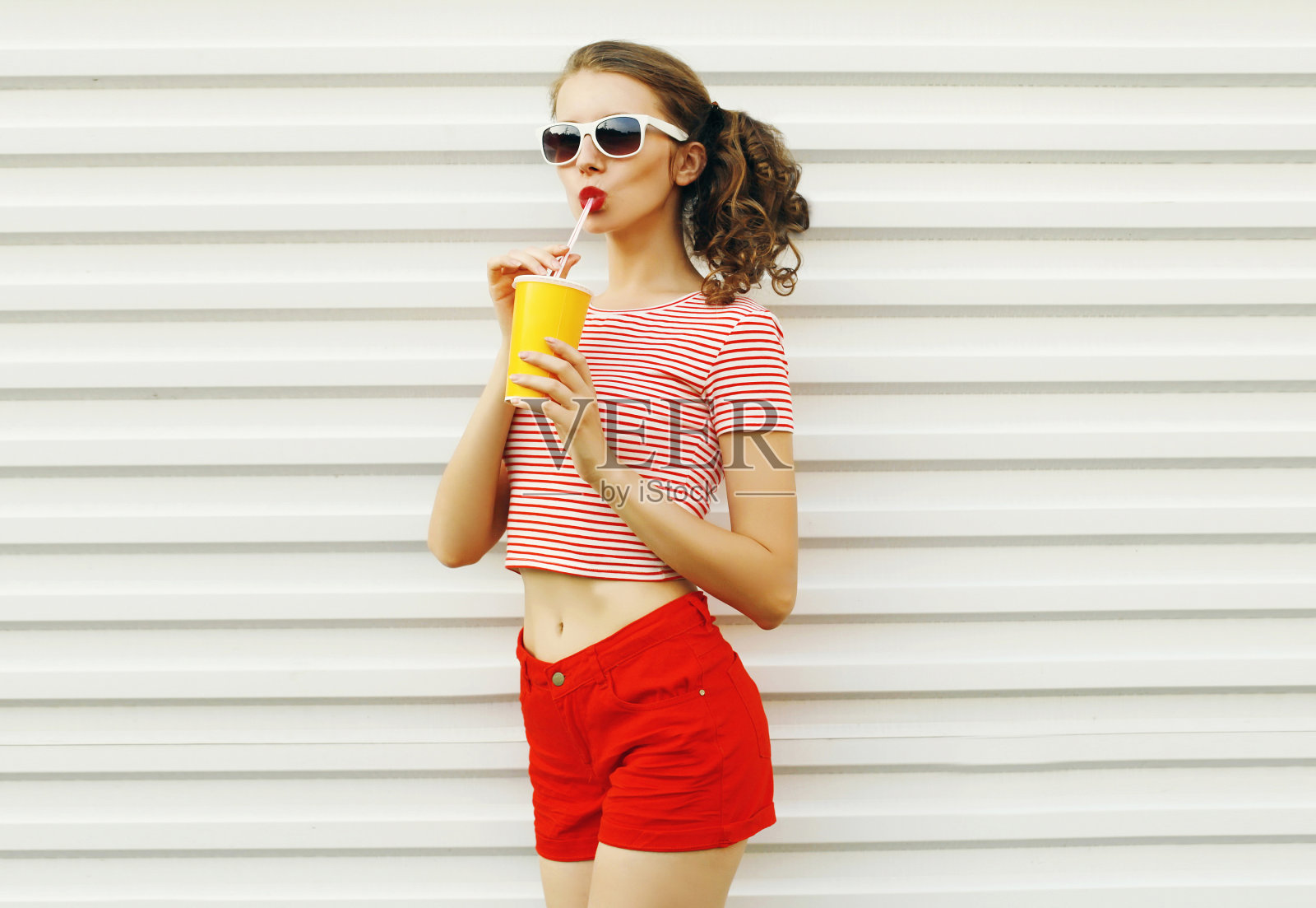 夏日肖像迷人的年轻女子喝果汁在白色的墙壁背景照片摄影图片