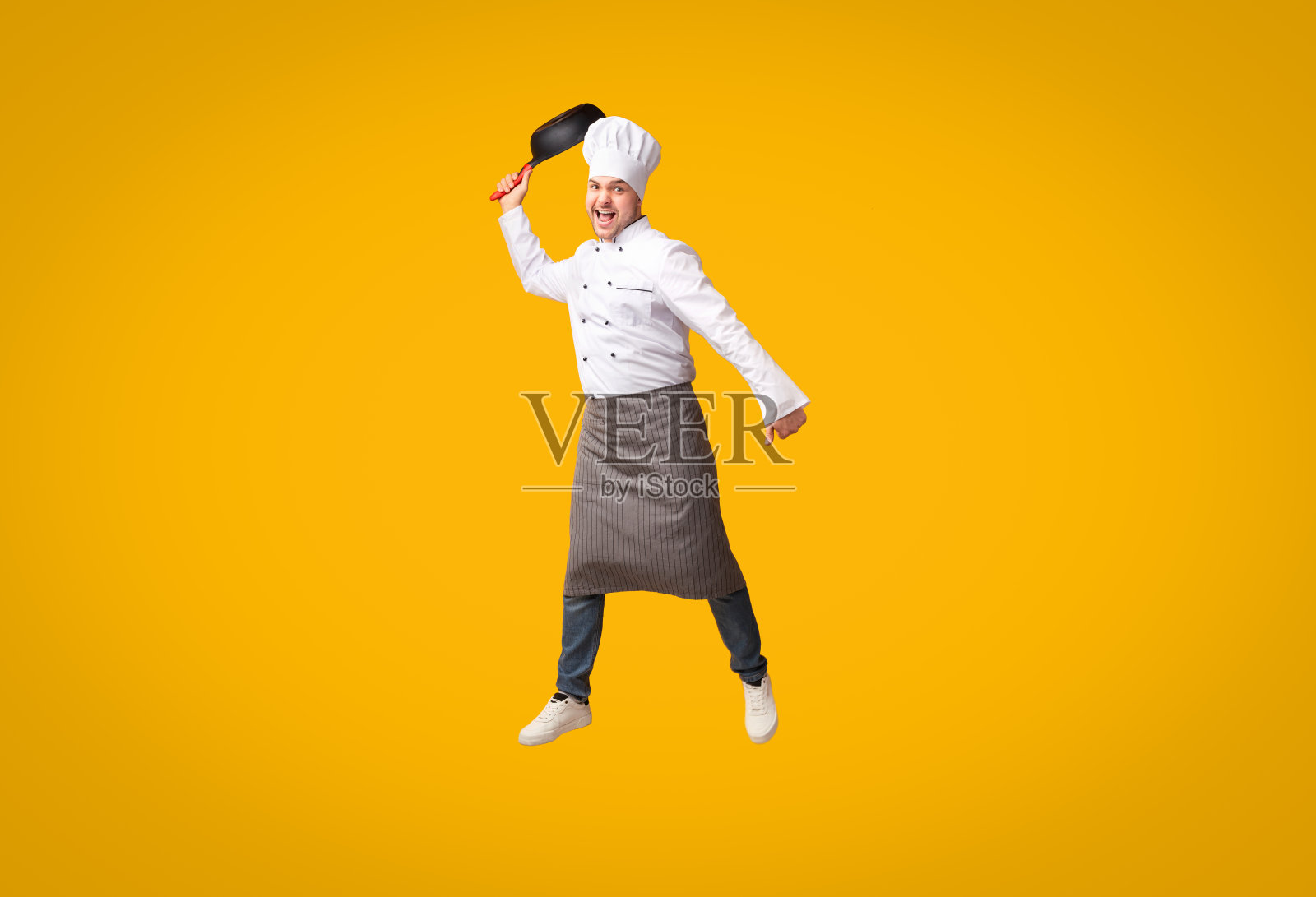 搞笑厨师跳起平底锅，黄色背景照片摄影图片