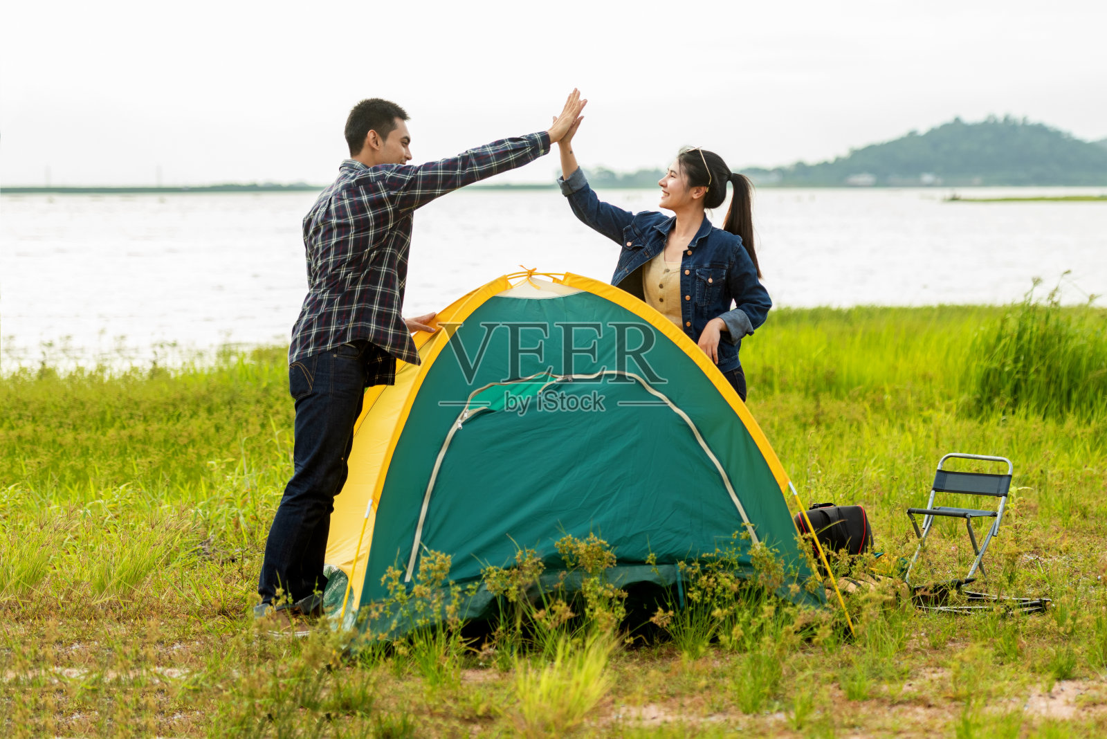 夫妇帮助安装帐篷露营户外附近的河流和草地。青少年团体家庭照片摄影图片