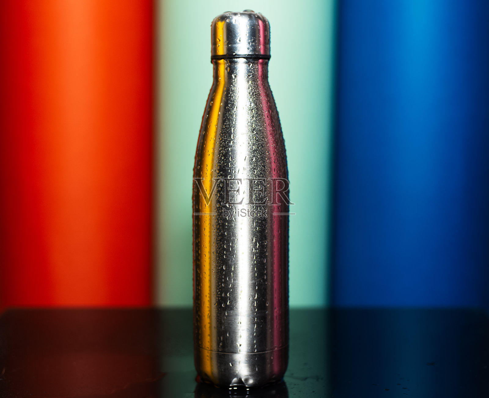特写的可重复使用的钢制热水瓶与水的背景郁郁葱葱的熔岩，薄荷水和幻影蓝色的颜色。照片摄影图片