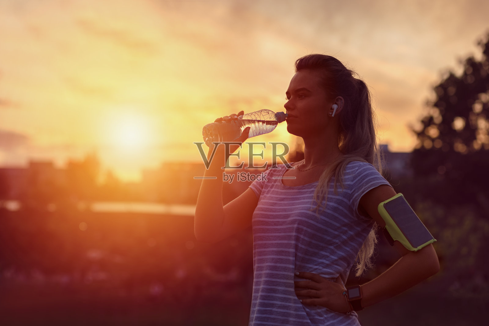 运动妇女在激烈的慢跑锻炼后的黎明在公园喝水照片摄影图片