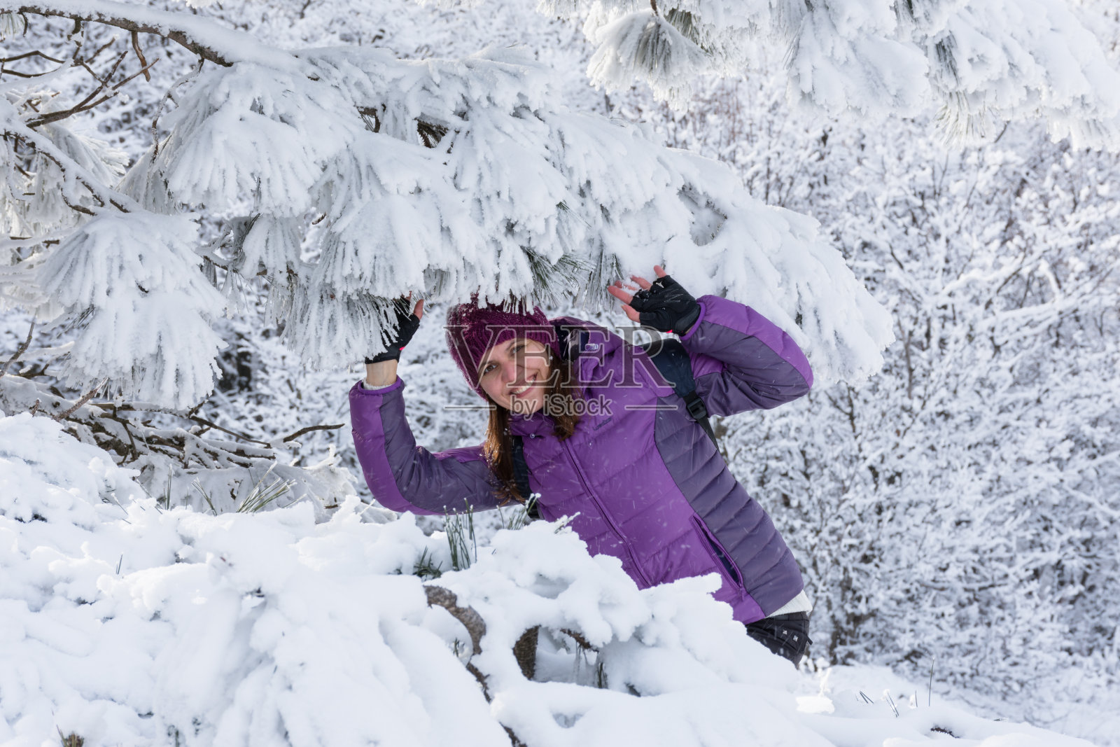 在雪树下，一个穿着滑雪服的女孩在冬日风景的背景下笑照片摄影图片