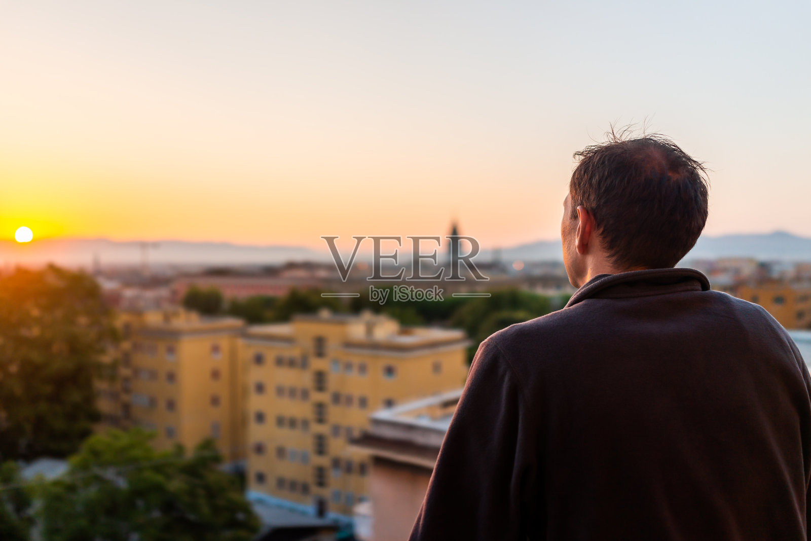 背影年轻男子看日落在罗马，意大利城市与教堂塔在夏季傍晚日落夜景城市天际线山鸟瞰图照片摄影图片