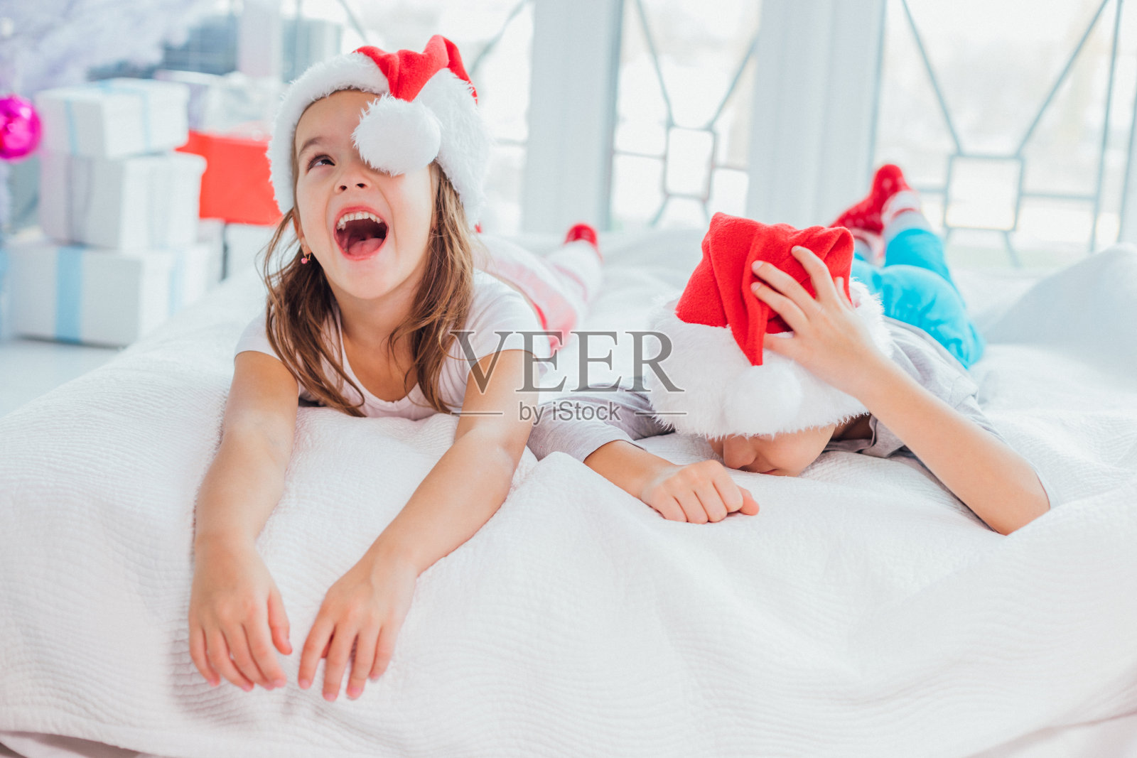 一个小女孩和男孩的特写肖像在圣诞节早晨的白色背景下的新年树。照片摄影图片