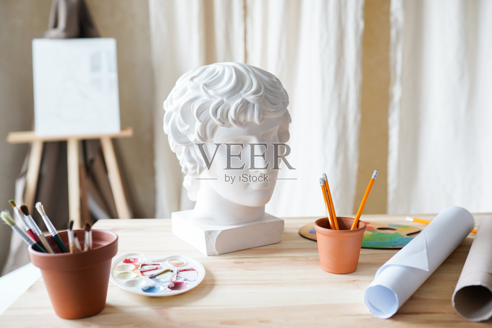 艺术工作室室内，石膏头，画笔和纸在桌子上。照片摄影图片