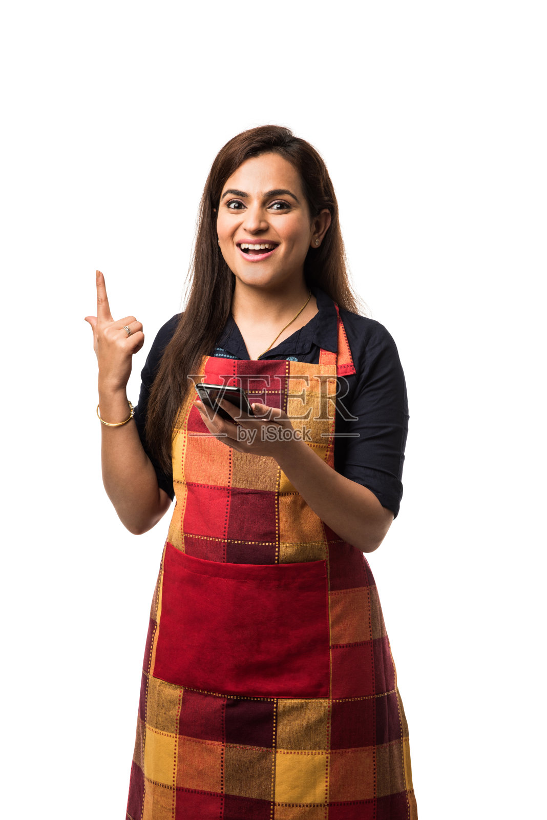 印度女厨师穿着围裙，孤立地站在白色背景下使用智能手机照片摄影图片