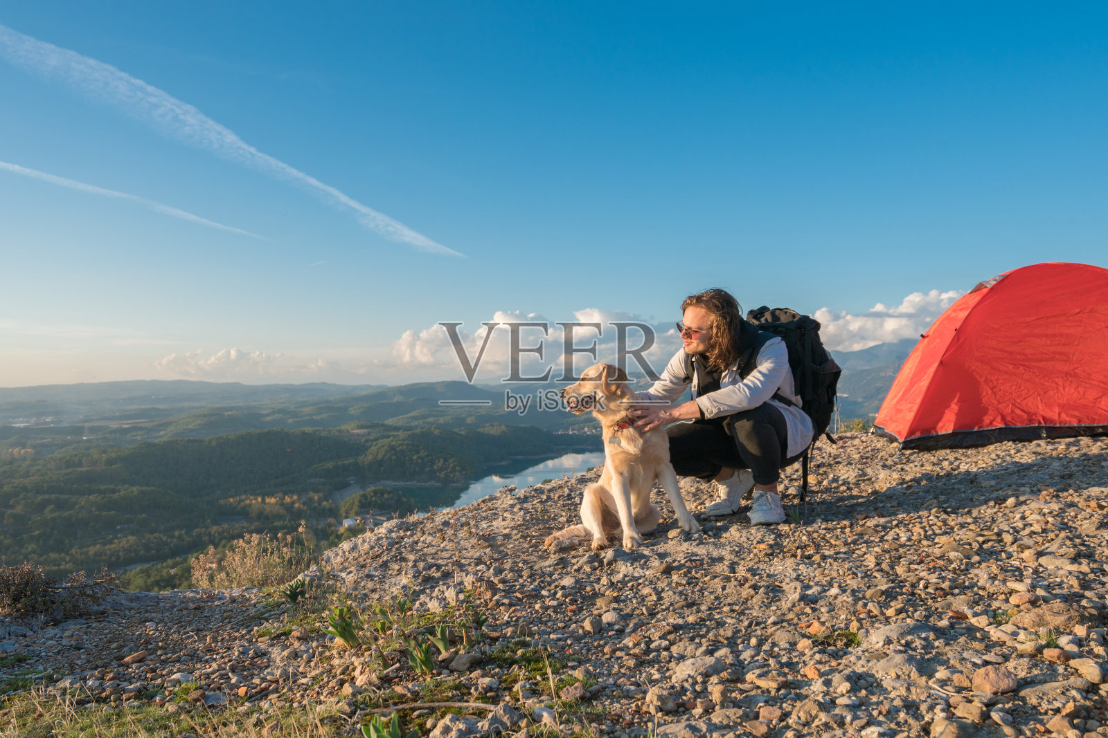 一个年轻人和她的狗在山顶露营照片摄影图片