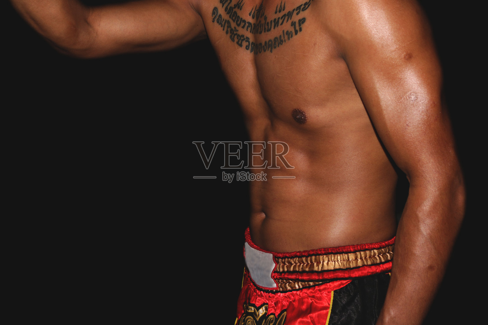 一位武术运动员的男模特展示了他的身体和腹部，前面有一个纹身照片摄影图片