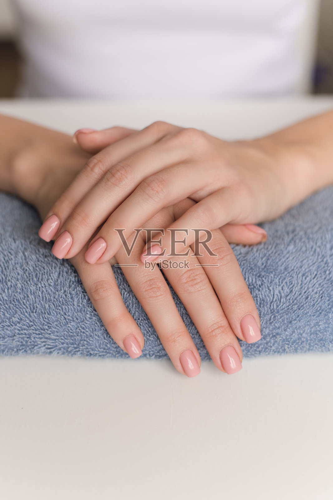 准备修指甲。一个年轻女孩的手躺在桌子上一条经典的蓝色毛巾上。裸体修指甲。手保健照片摄影图片