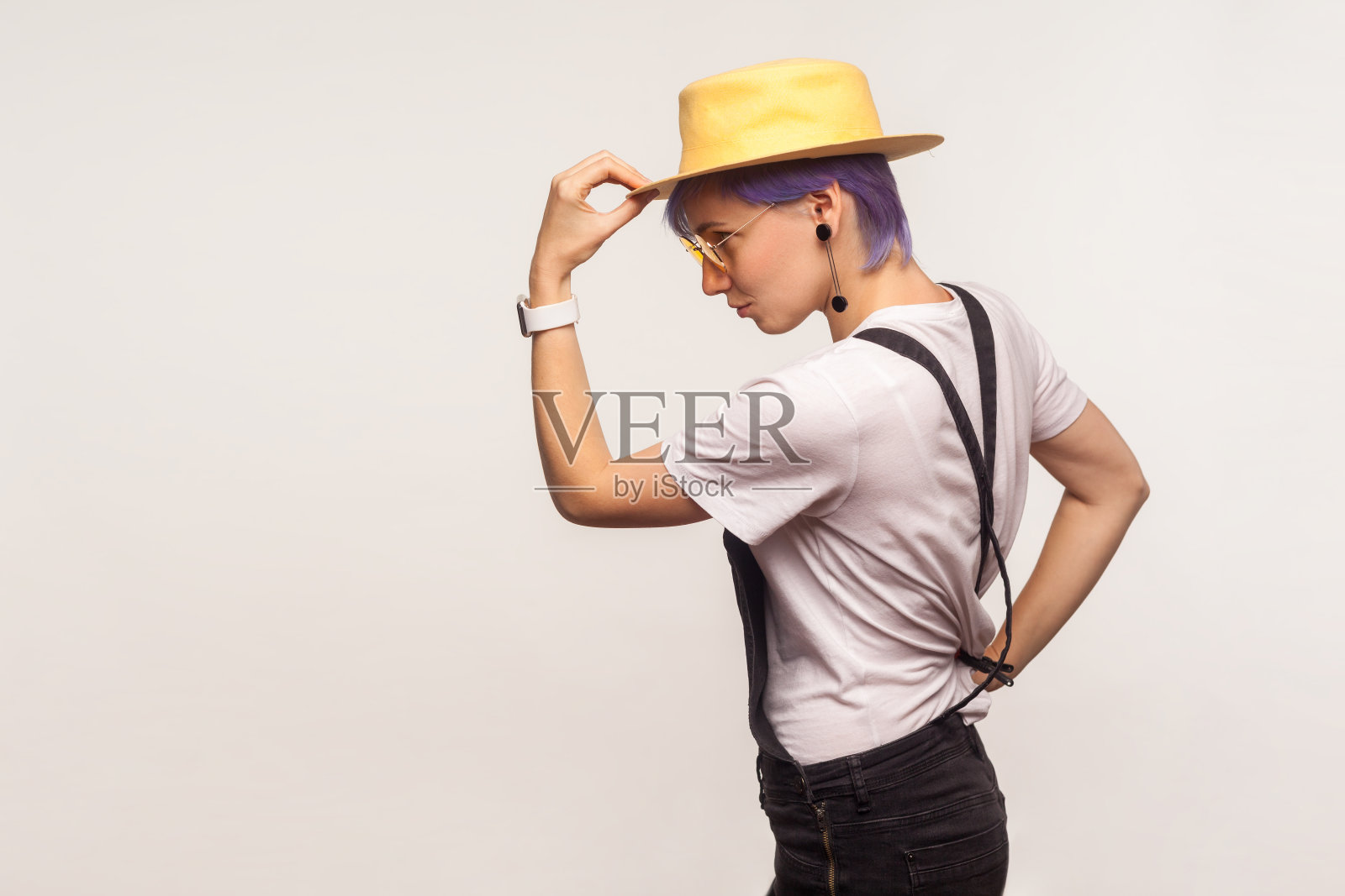 侧视图肖像优雅时尚的嬉皮士女孩拿着帽子在头上，看空的空间。白色背景，工作室拍摄照片摄影图片