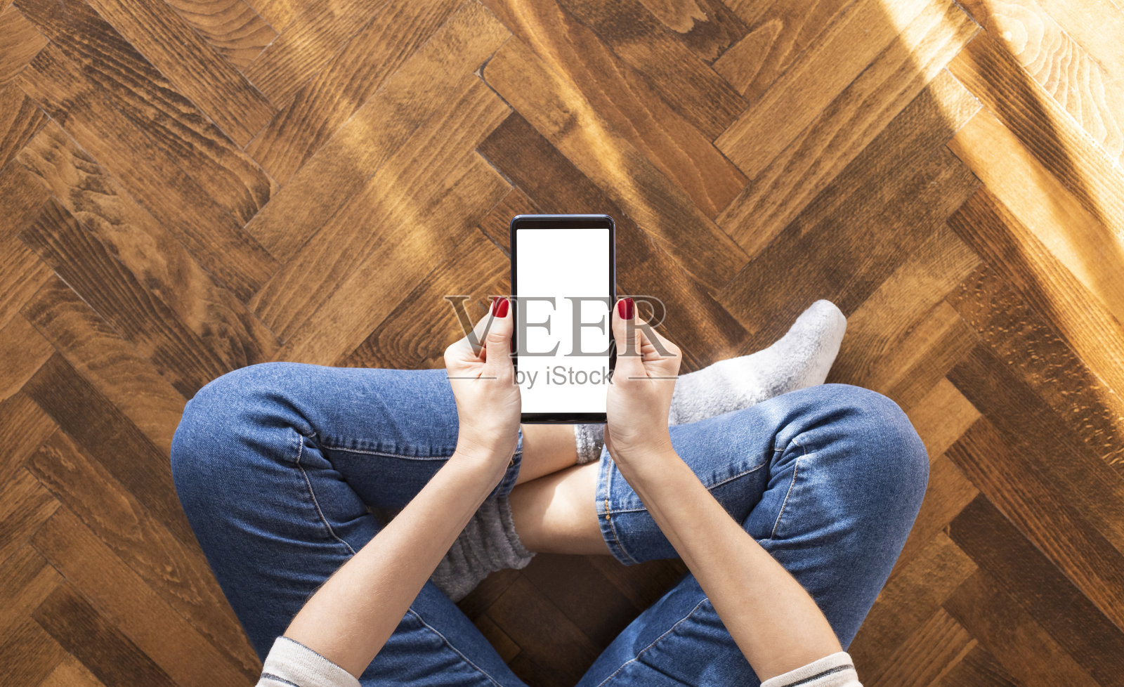 年轻女子坐在家里的地板上，正在用手机照片摄影图片