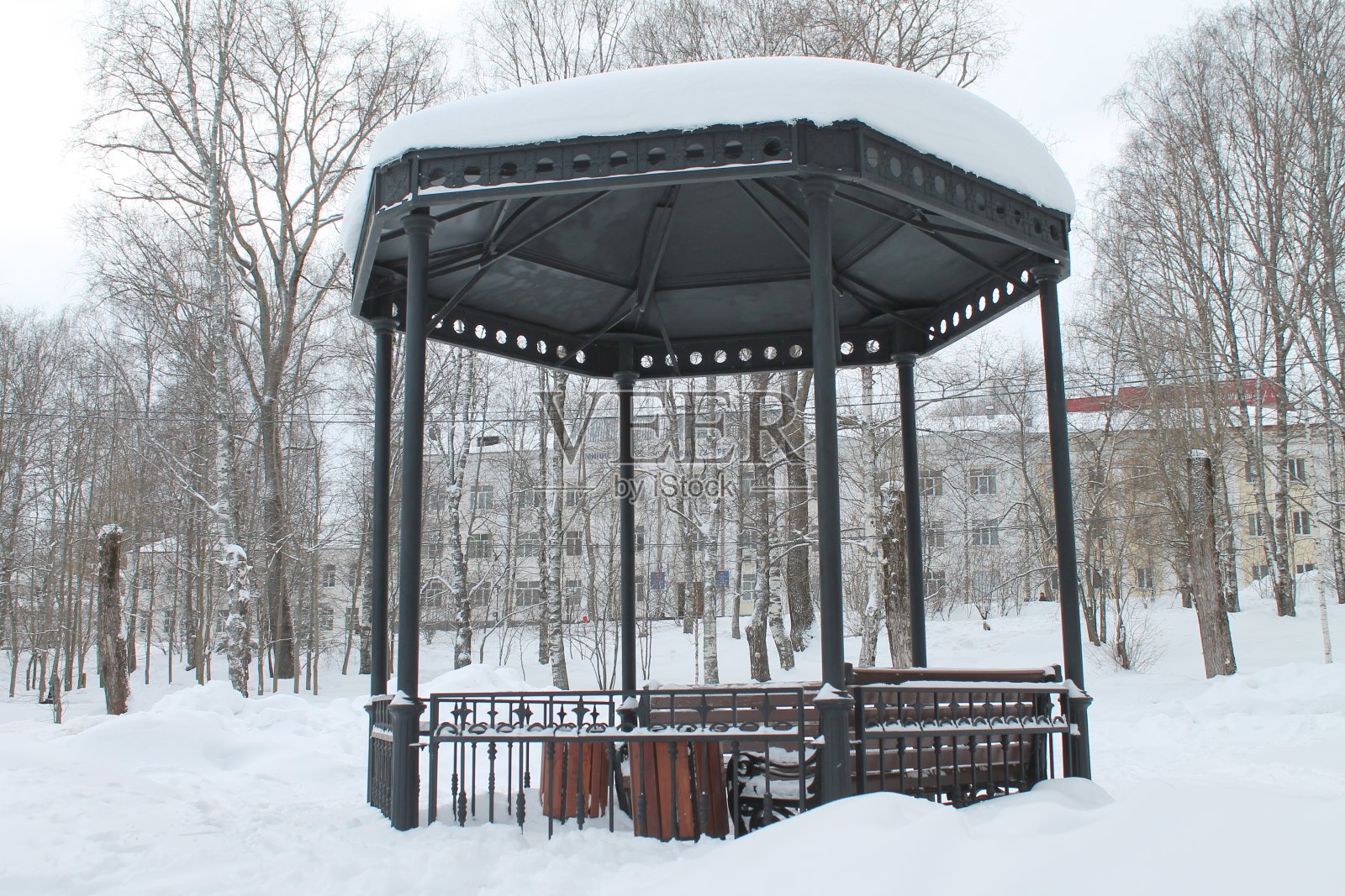 公园里有长凳的金属露天凉亭，阴天被雪覆盖照片摄影图片