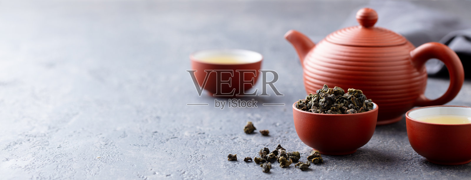 青茶乌龙茶在一个粘土茶杯碗和茶壶。石头背景。副本的空间。照片摄影图片
