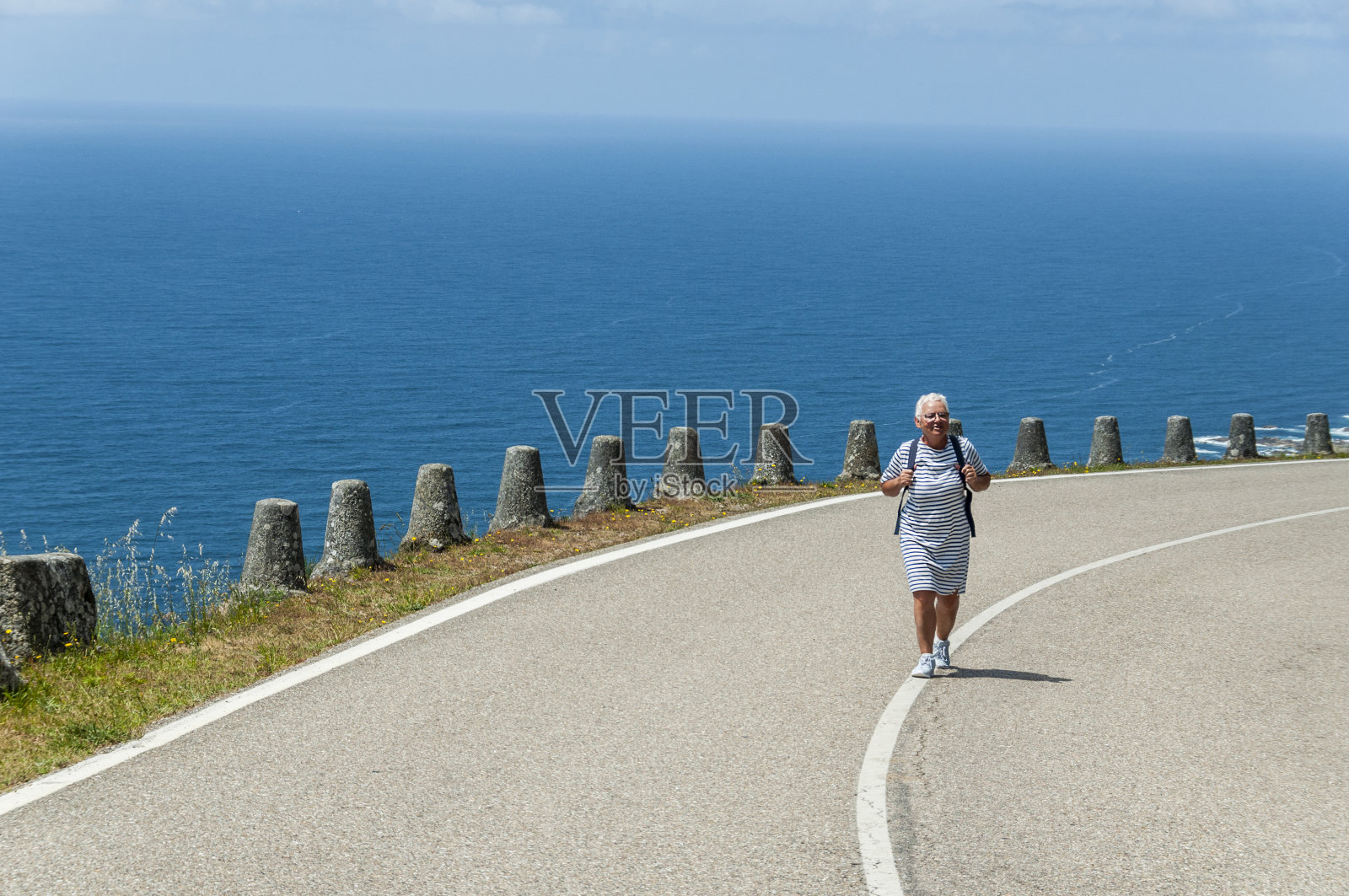 一个女游客走在美丽的海边。照片摄影图片