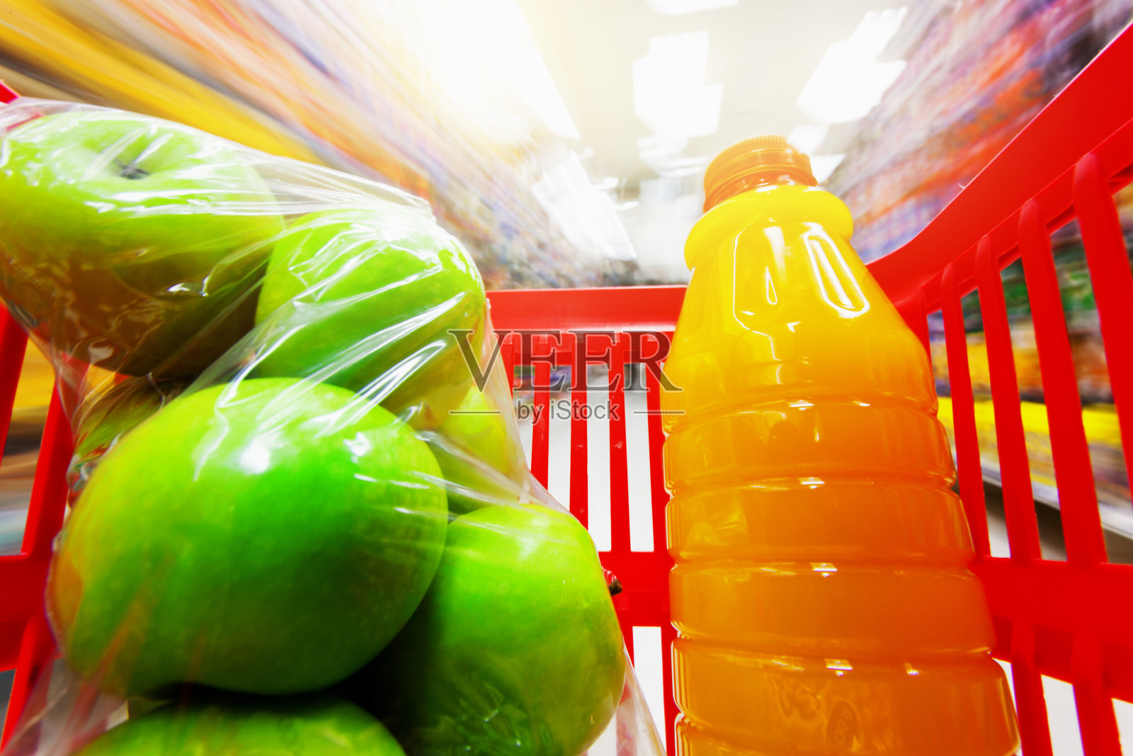 塑料包装的苹果和橙汁在购物车的特写照片摄影图片