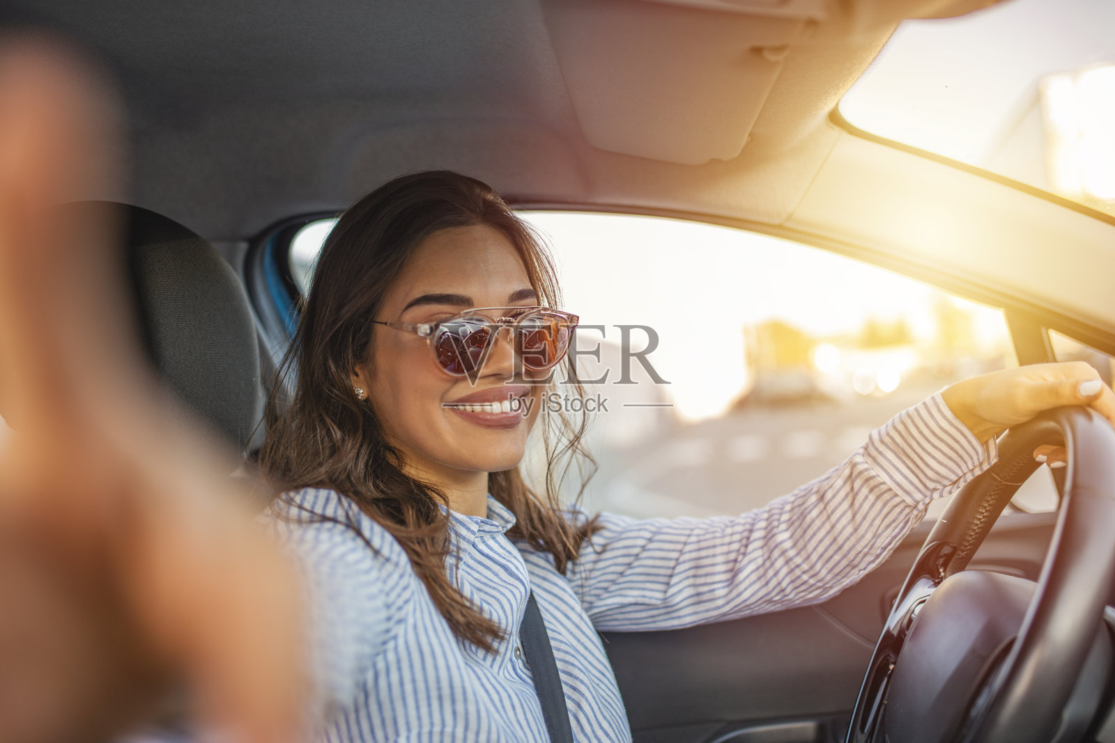微笑的年轻女子与智能手机相机自拍在户外的汽车。照片摄影图片