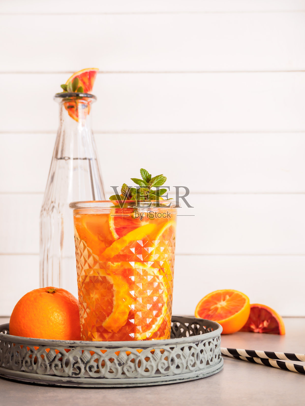 用玻璃杯装上新鲜的橘子和水，放在托盘上，自制柠檬水照片摄影图片