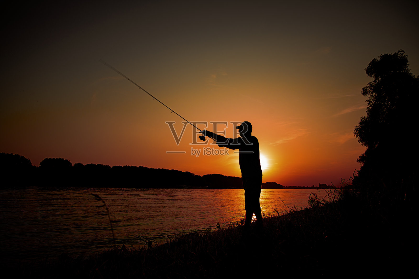 日落时分，人们在河边钓鱼照片摄影图片