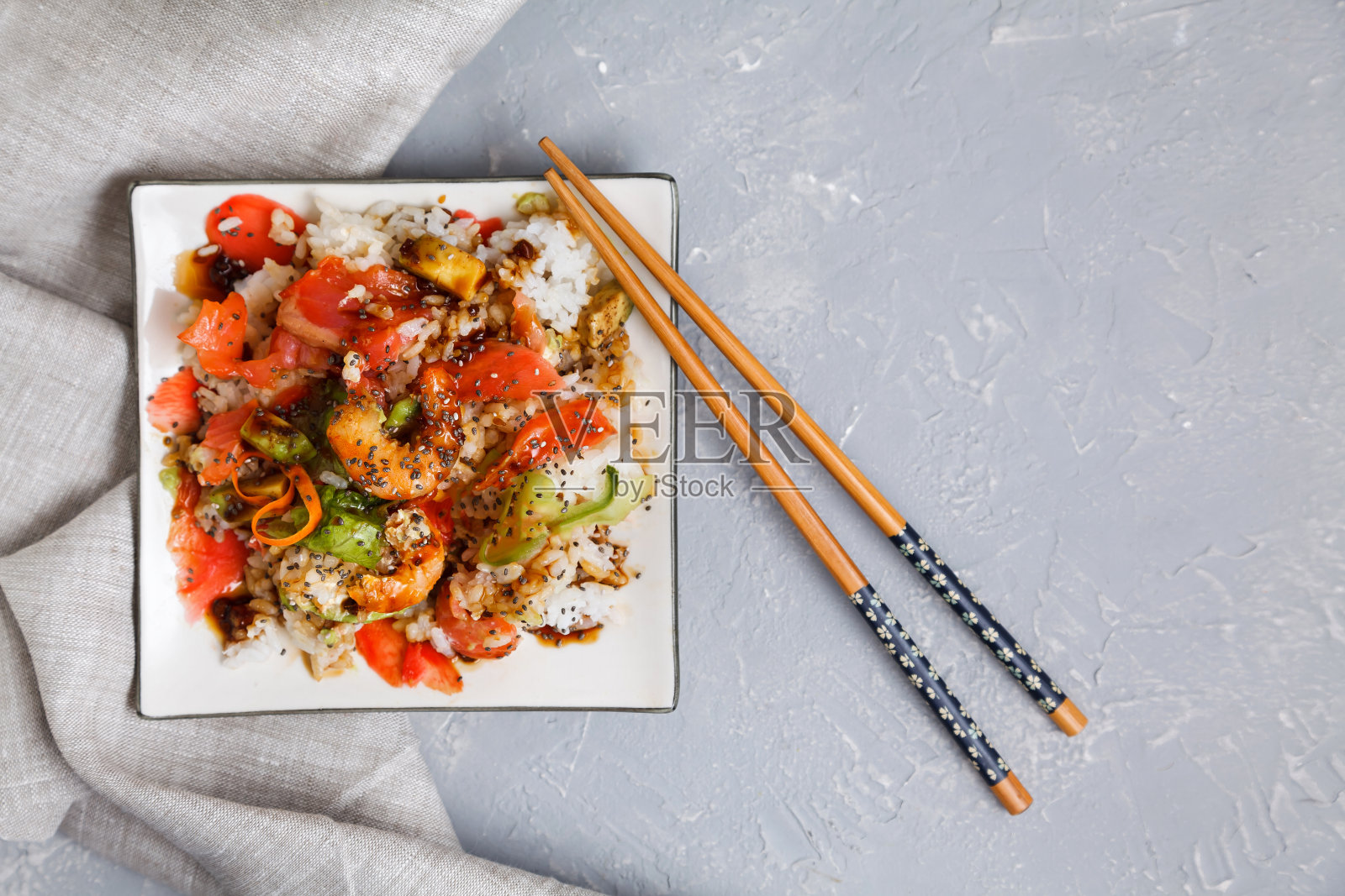 俯视图的盘子上有一个戳沙拉海鲜，米饭和蔬菜，鳄梨和奇亚籽酱油和芥末在碗和哈西棒。照片摄影图片