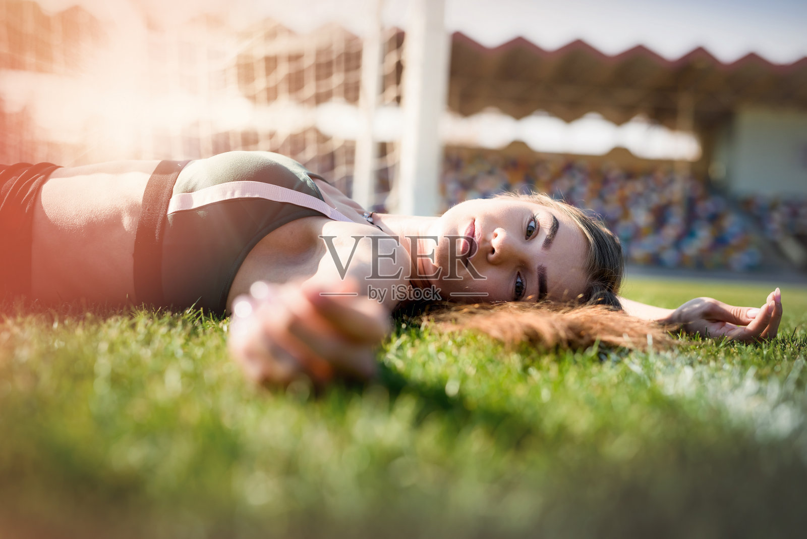 一个年轻女子在运动后休息或在体育场跑步的肖像。健身和健康生活理念。照片摄影图片