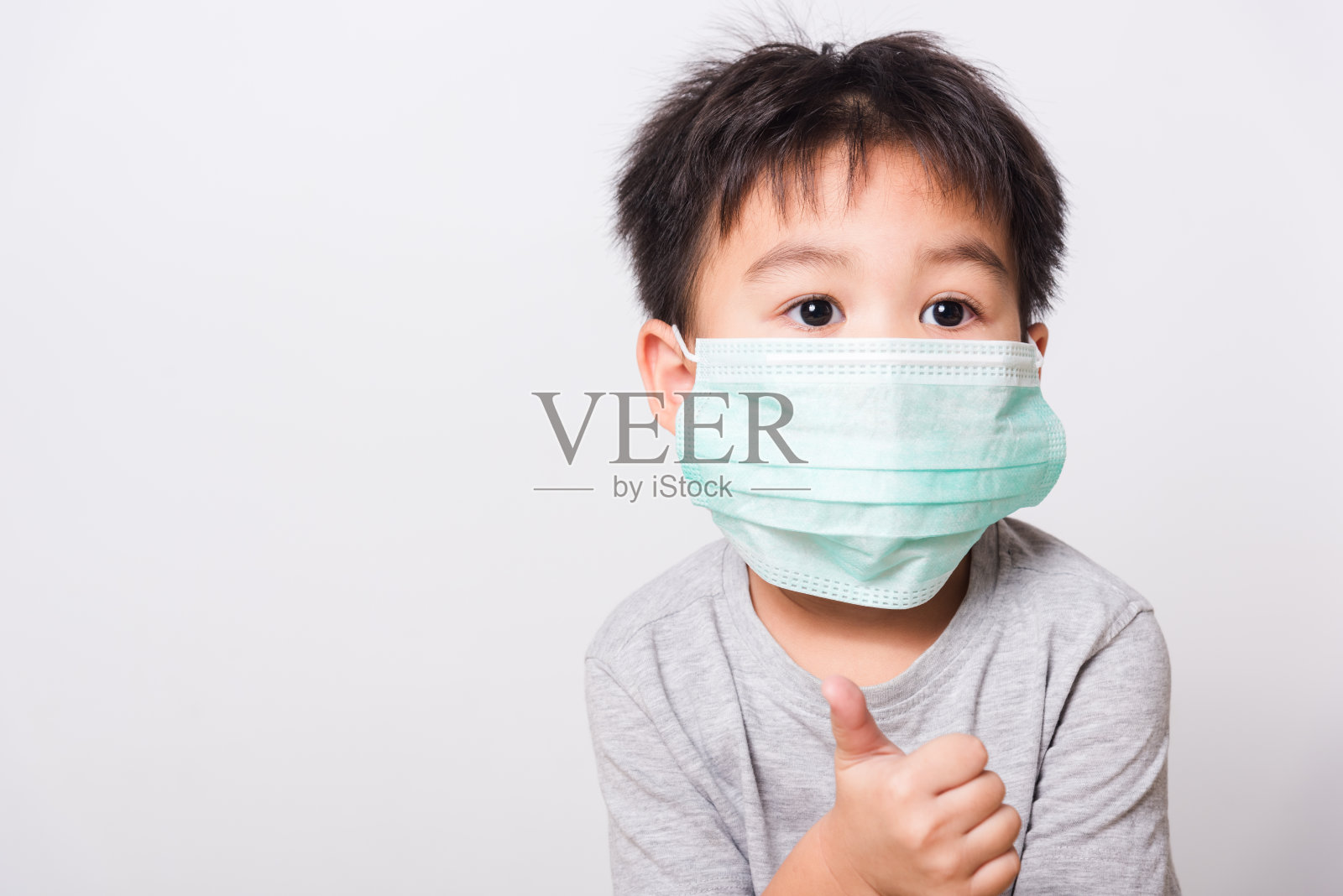 特写亚洲人的脸，生病的小男孩他在白色的背景上使用药物保健面具照片摄影图片