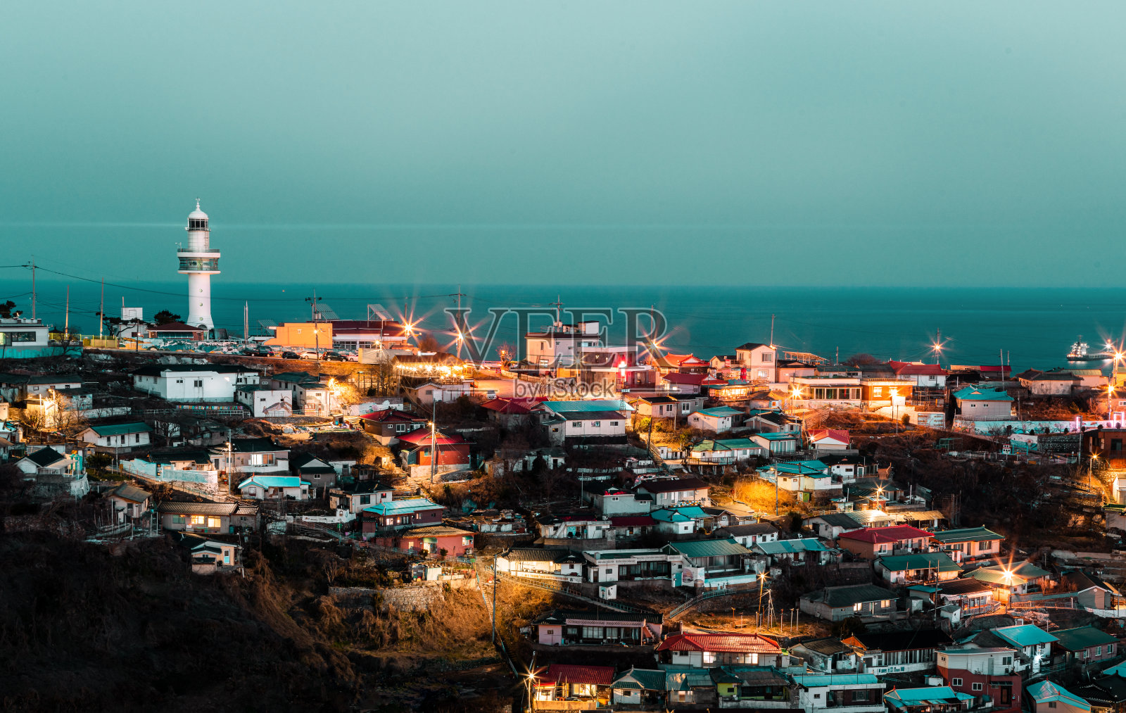 韩国海港村夜晚的灯塔。照片摄影图片