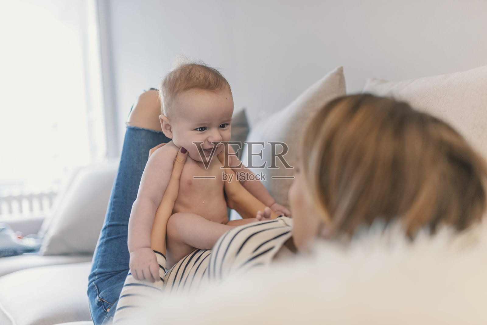 妈妈和男婴穿着尿布在阳光明媚的客厅里玩耍照片摄影图片