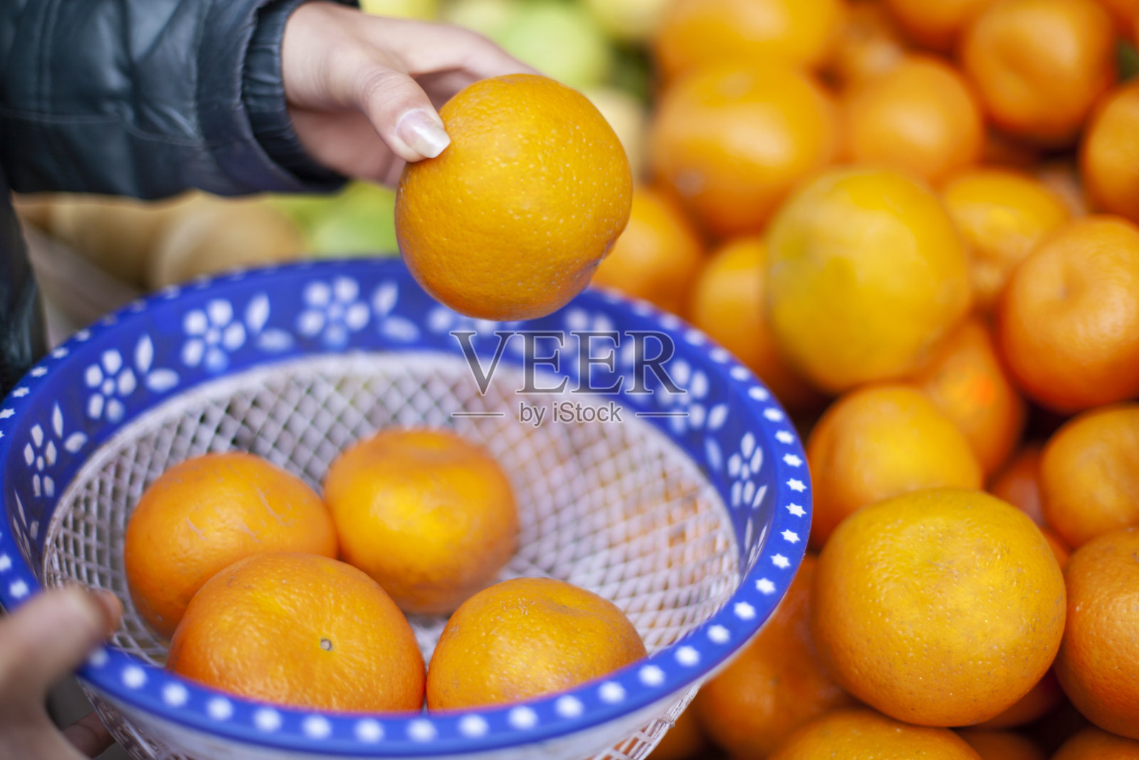 女人的手从水果店买新鲜橙子的特写。照片摄影图片