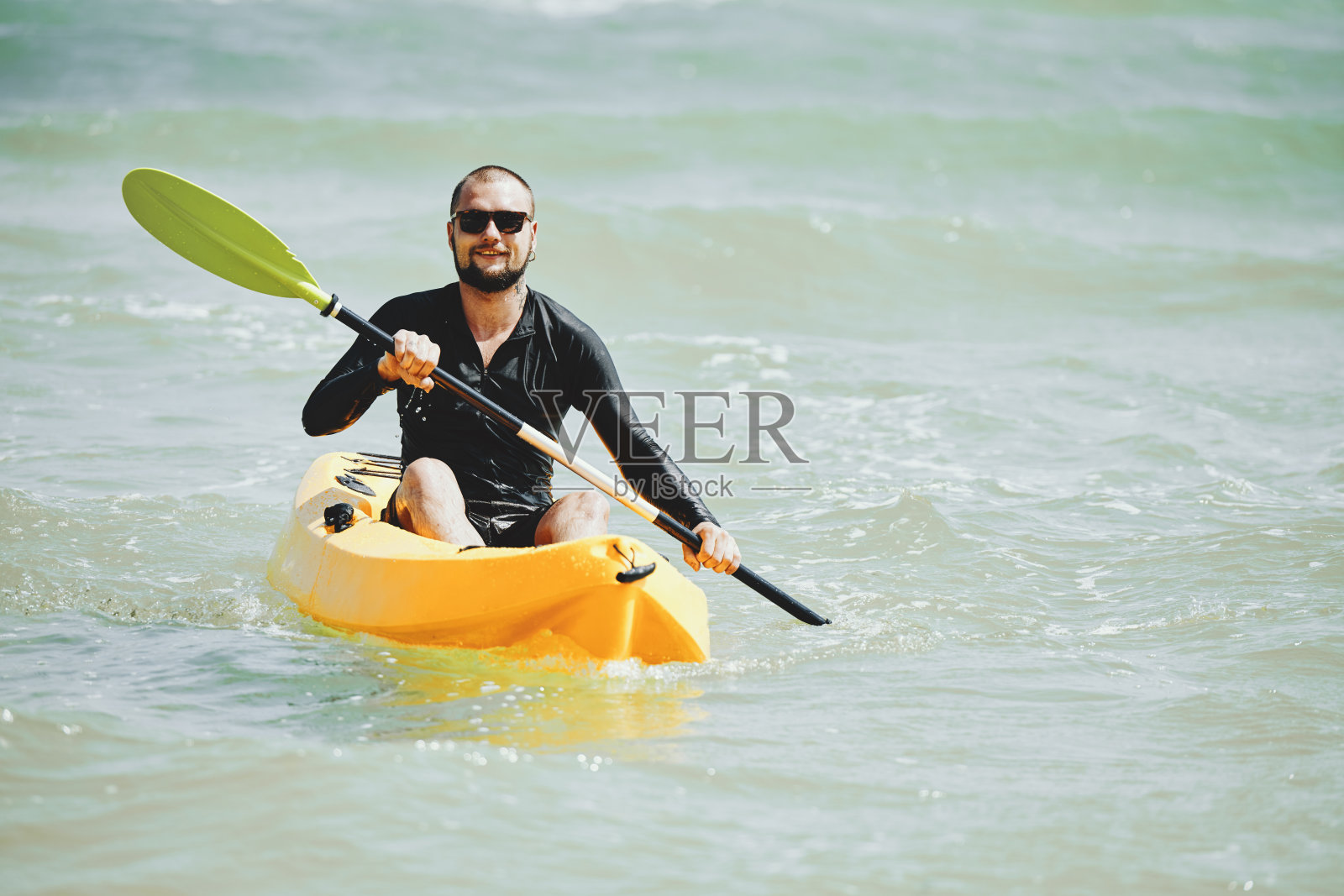 在温暖的海上划皮艇的人照片摄影图片