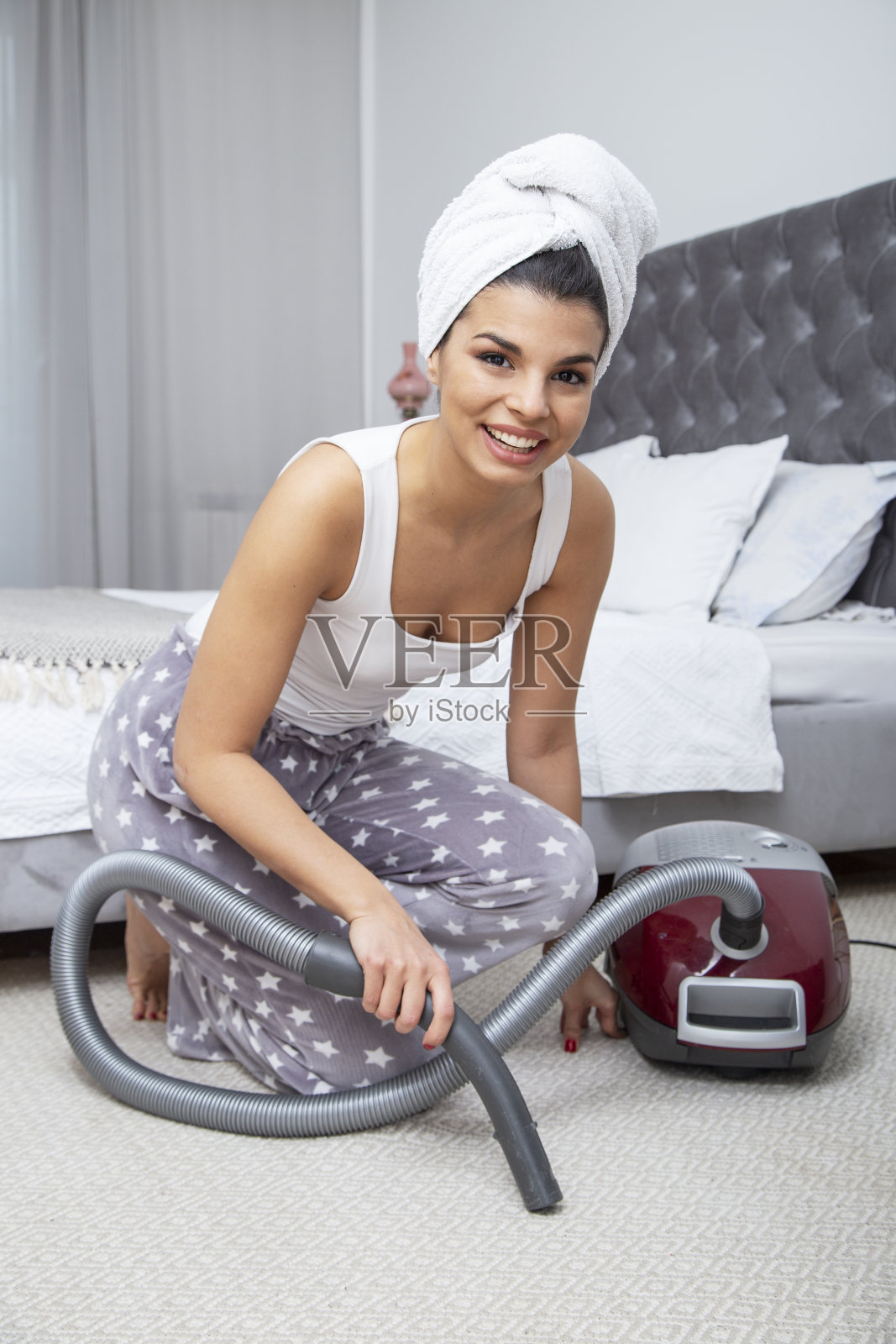 快乐女人用吸尘器吸卧室地毯照片摄影图片