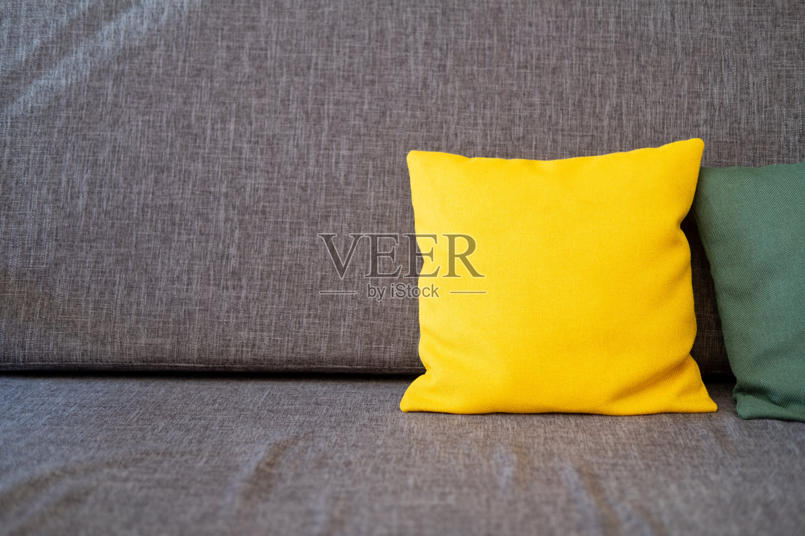 装饰灰色沙发的亮黄色靠垫。照片摄影图片