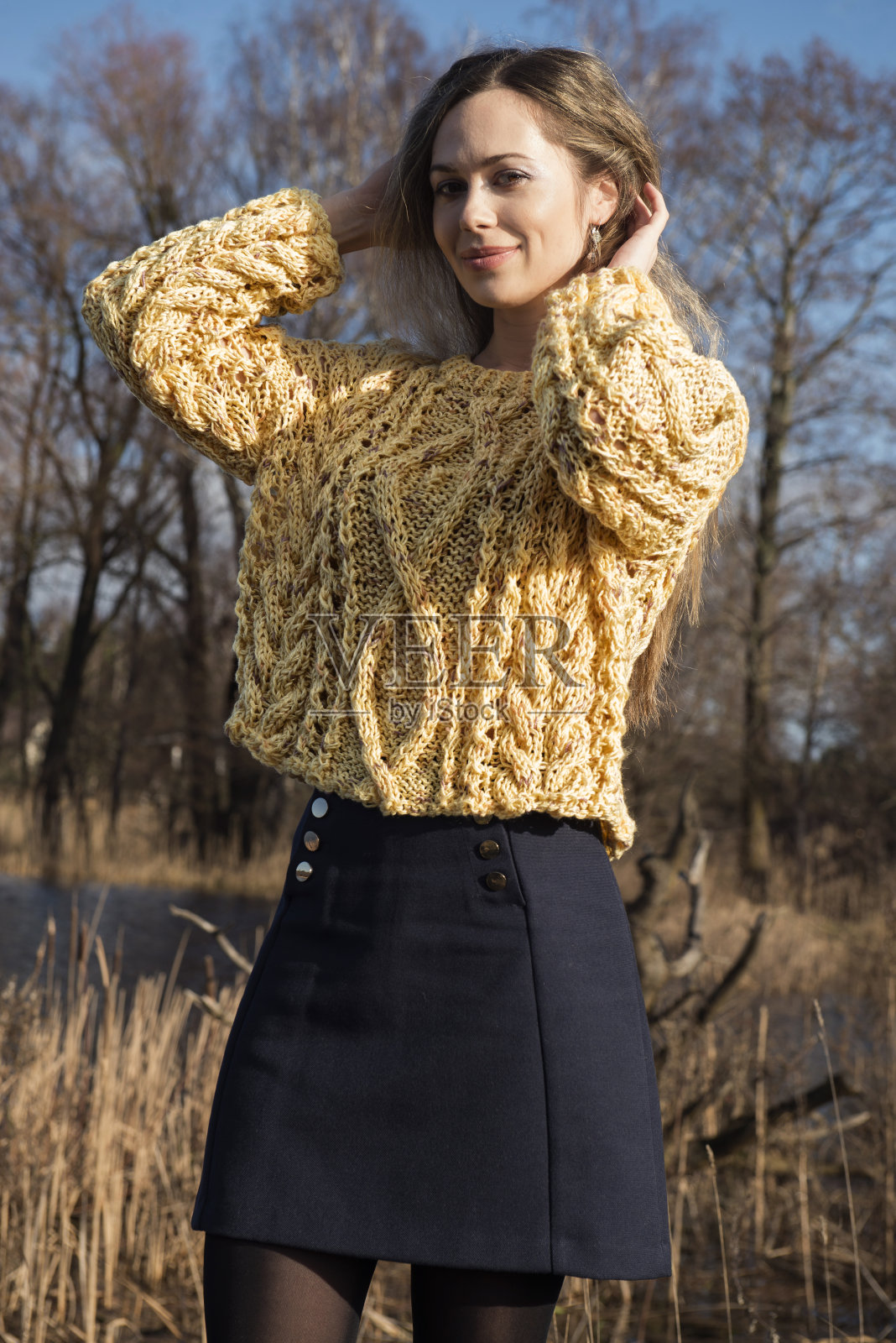 一个女人穿着手工制作的黄色针织毛衣摆姿势在湖边散步的早晨照片摄影图片