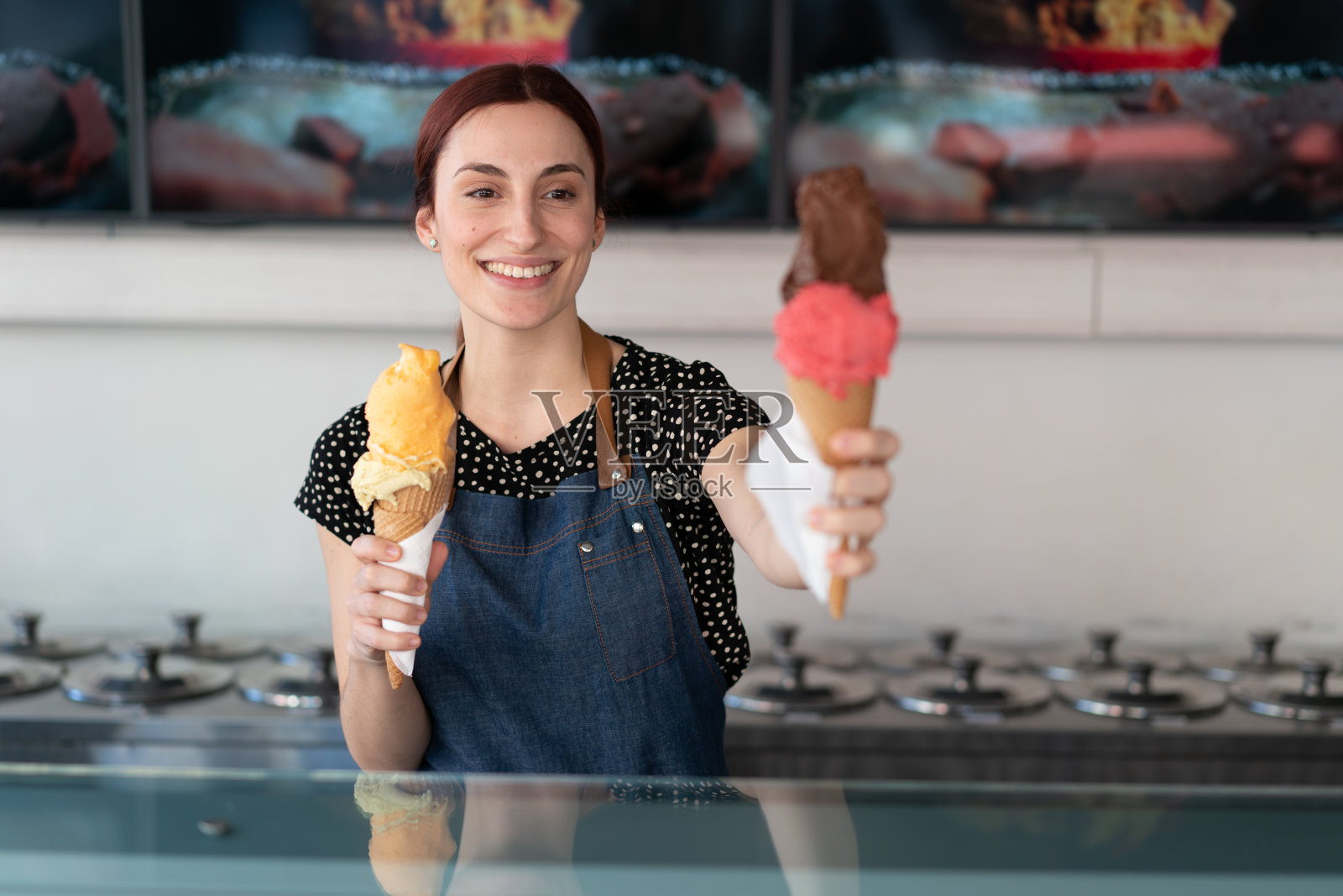 微笑的女售货员在冰淇淋店拿着冰淇淋的肖像照片摄影图片