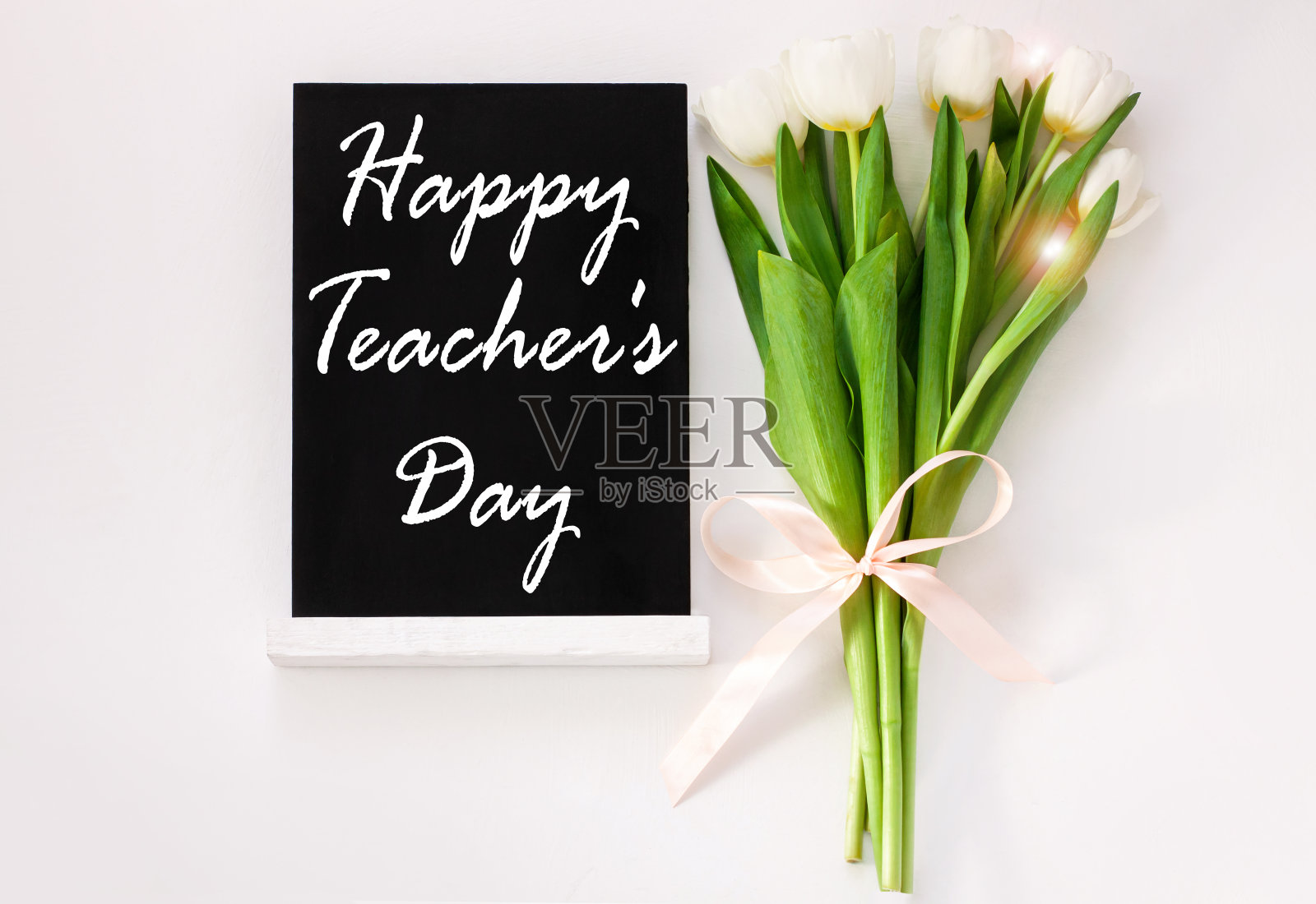 国际教师节海报设计标志在黑色的黑板和郁金香花在白色的背景。回到学校照片摄影图片