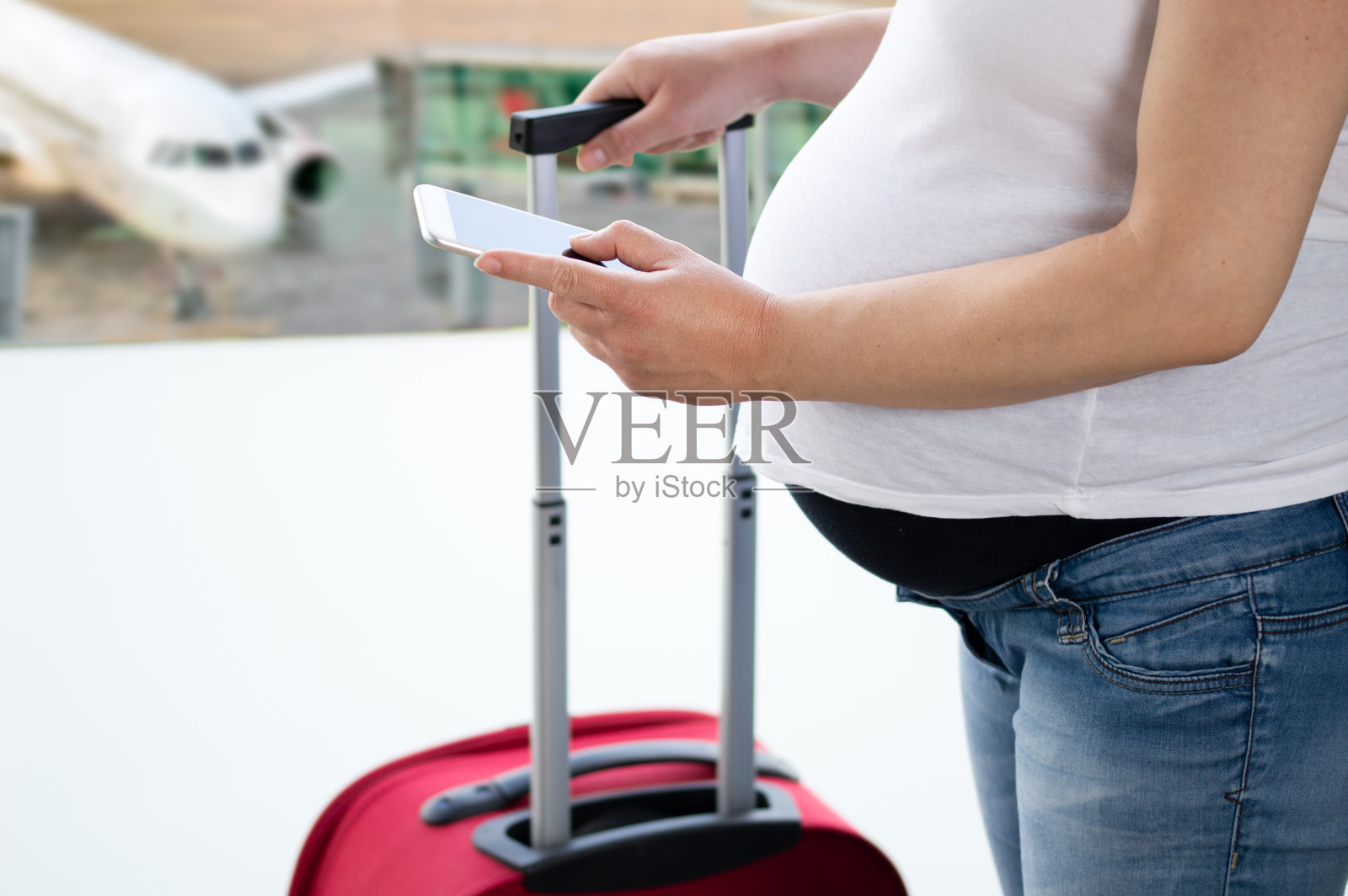 一名孕妇在机场看智能手机照片摄影图片