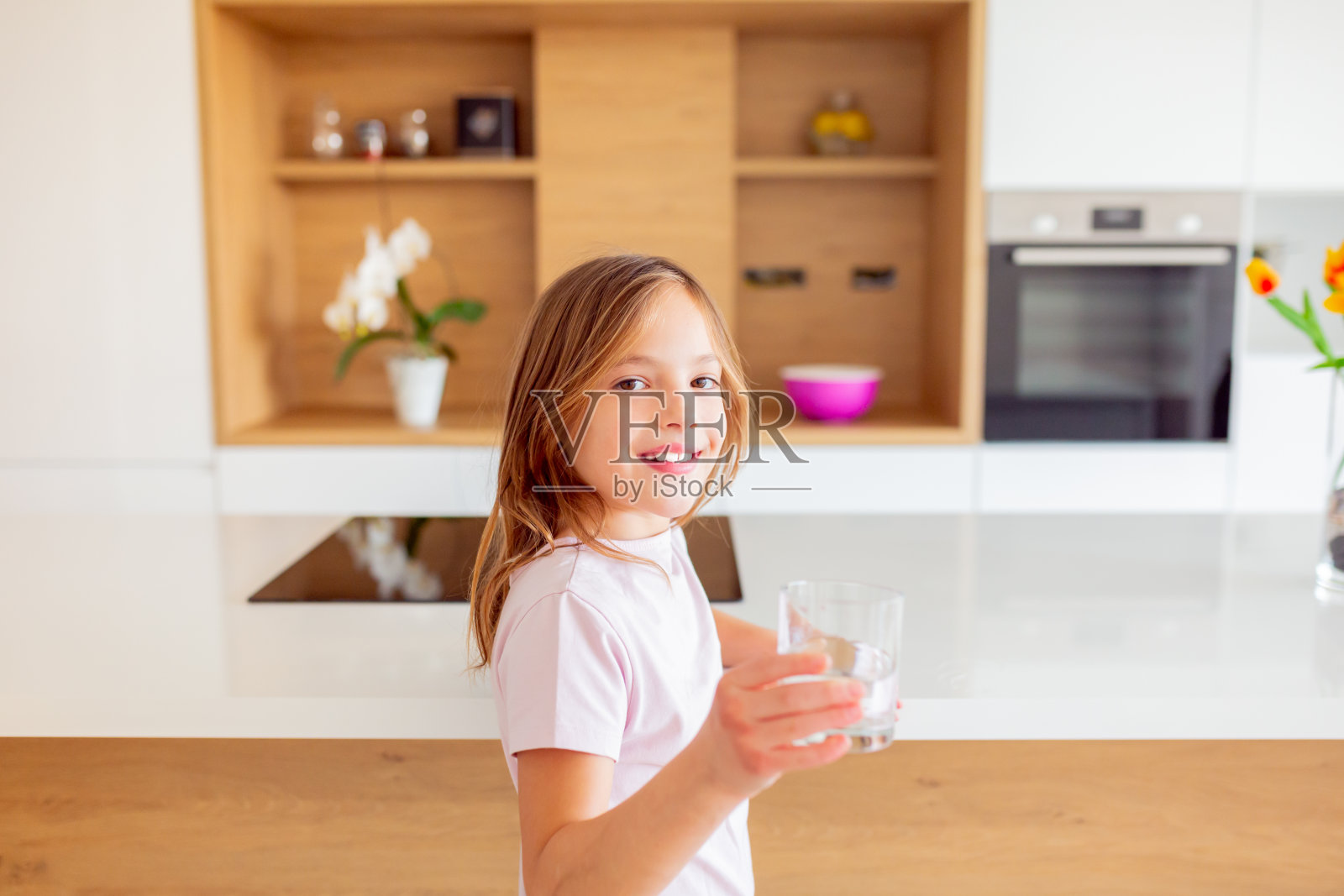 小女孩在厨房里从杯子里喝水照片摄影图片