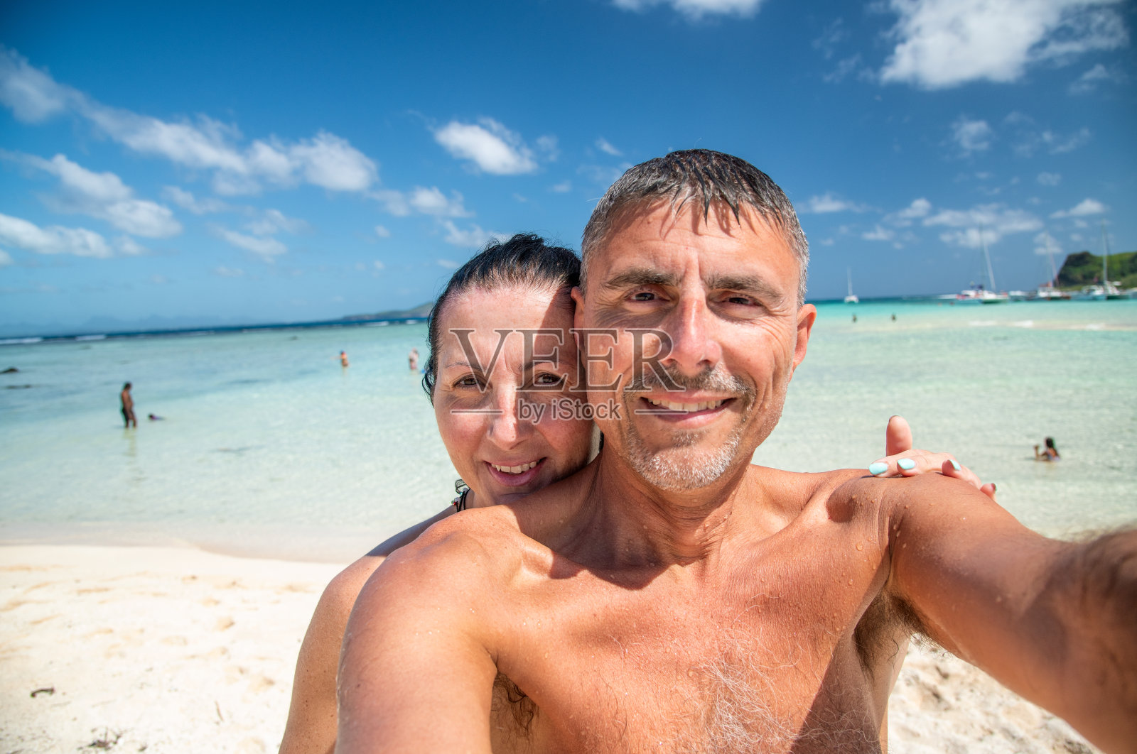 幸福的一家人在海滩度假。一对年轻情侣在海岸线上拥抱自拍照片摄影图片