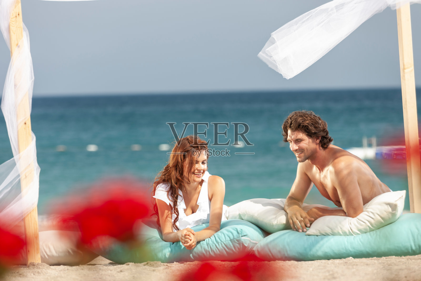 在阳光明媚的日子里，一对快乐的年轻夫妇在海滩上的木制露台上玩耍照片摄影图片