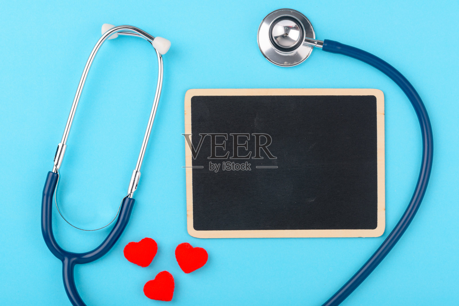 医生日概念，平躺俯视图，听诊器与红色心脏和黑色板在蓝色背景照片摄影图片