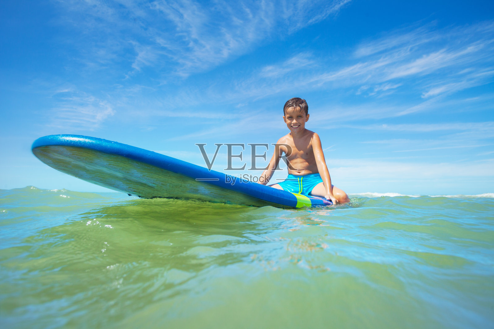 小男孩坐在冲浪板上等待海浪照片摄影图片