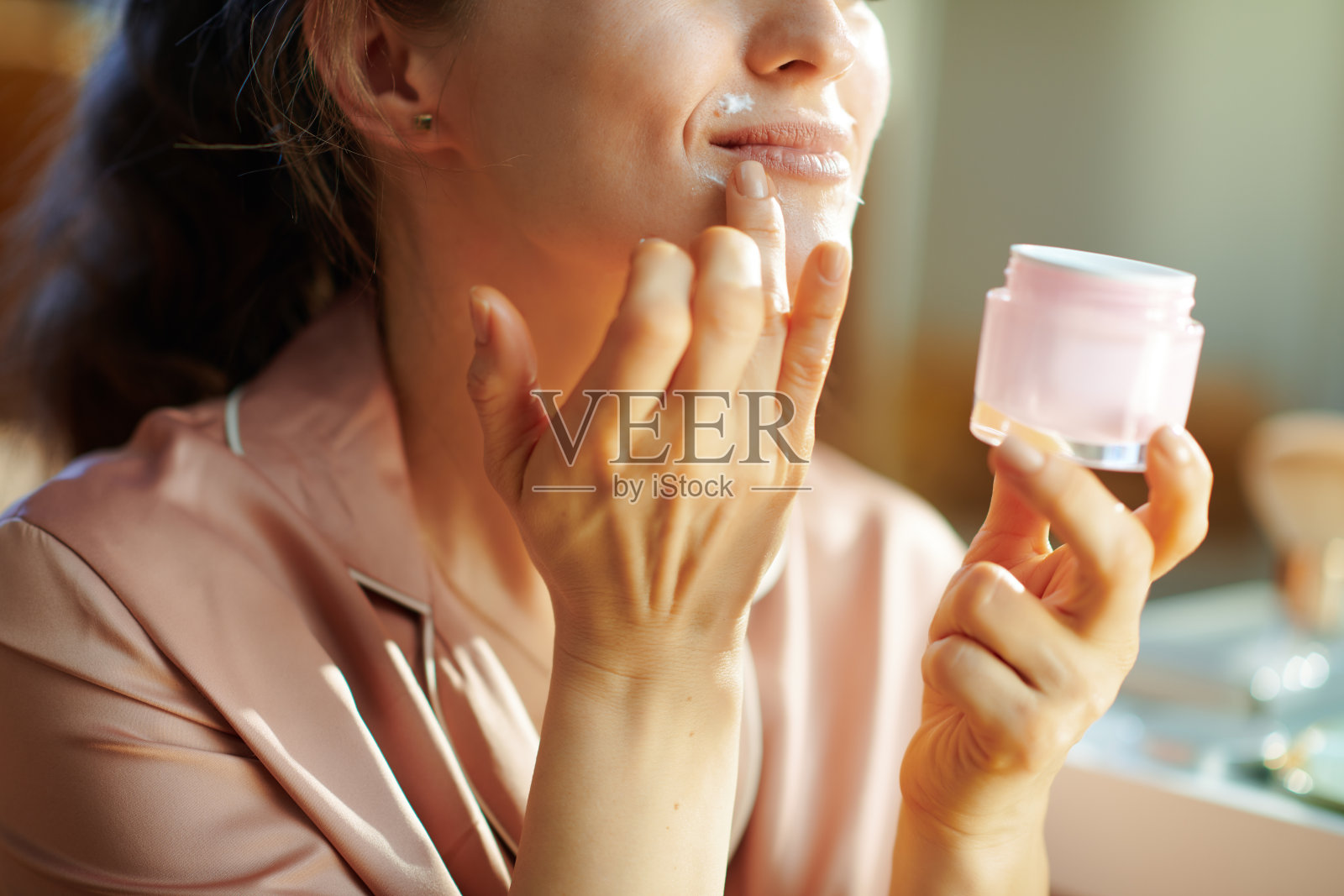 快乐的现代女性与化妆品罐应用嘴唇轮廓霜照片摄影图片