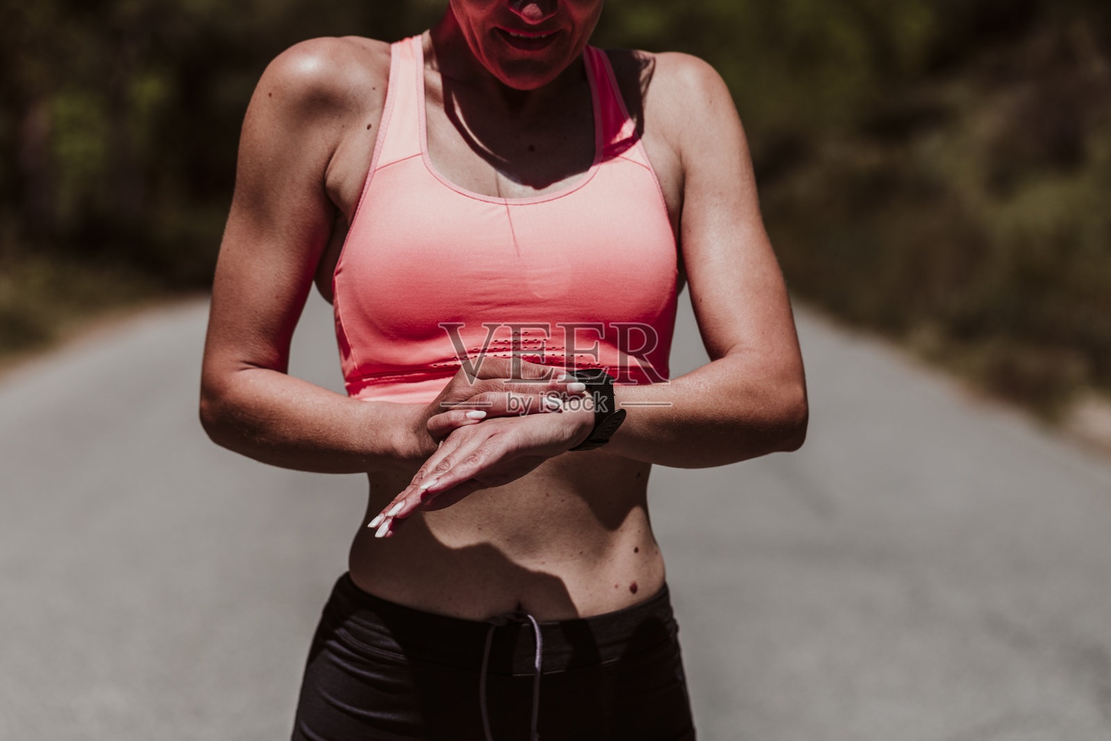 一个40多岁的女人在阳光明媚的日子里在户外锻炼，看智能手表。健康生活和运动生活理念照片摄影图片