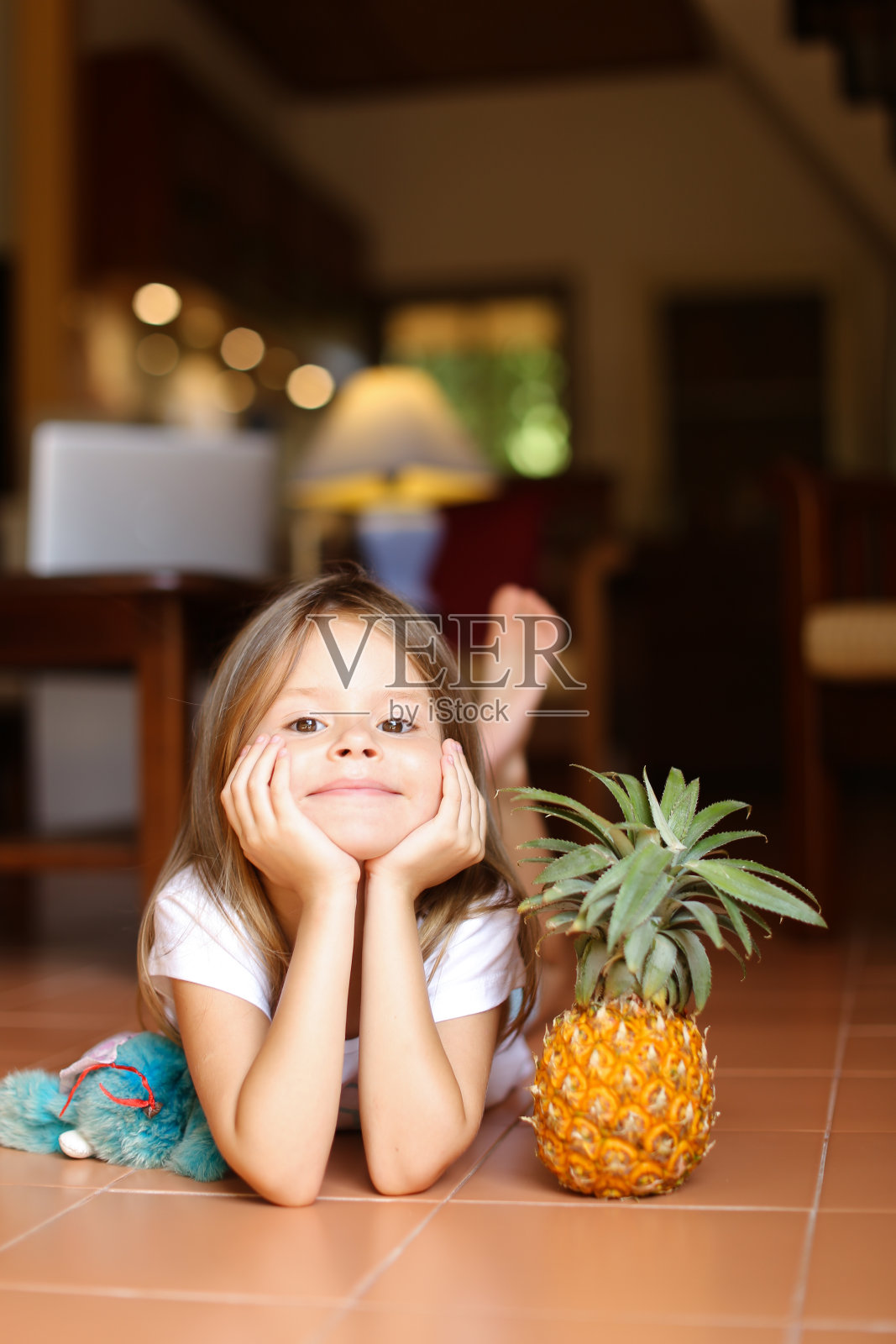 小女孩的肖像躺在地板上和菠萝和玩具照片摄影图片