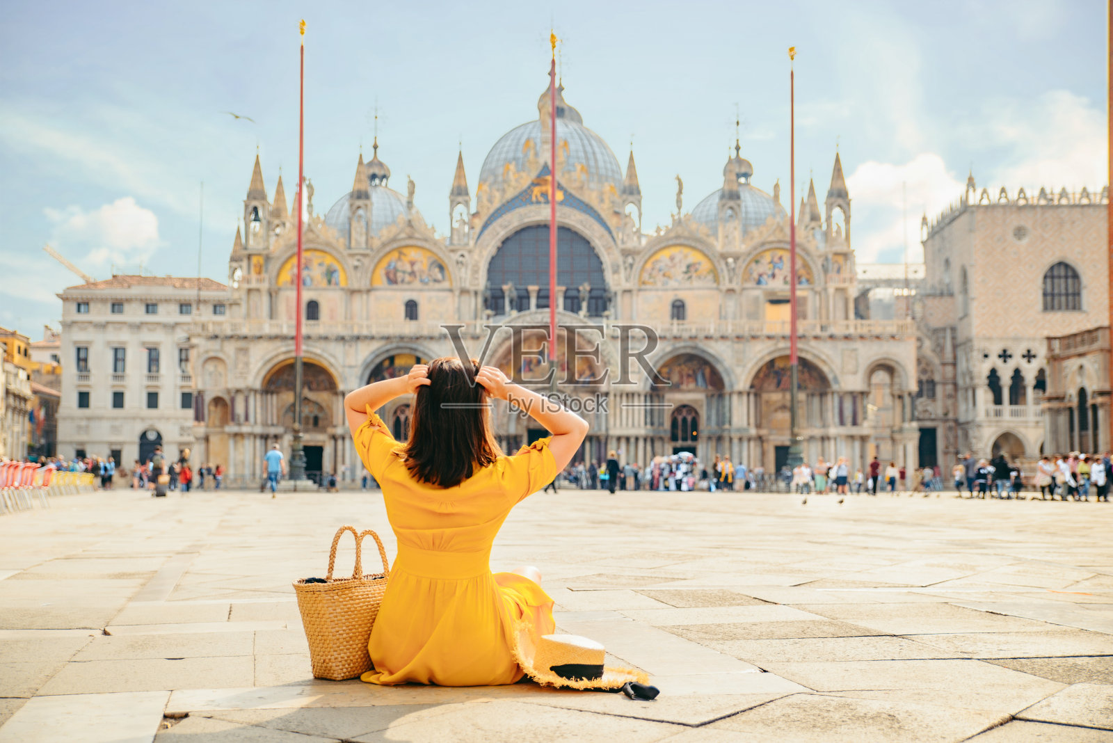 身着黄色太阳裙的女子坐在地上欣赏圣马可大教堂的景色照片摄影图片