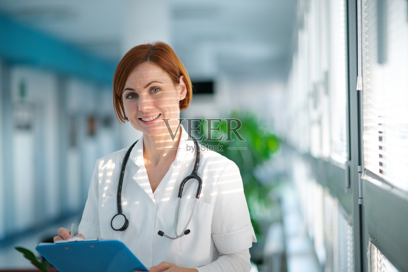 一幅女医生站在医院里写作的肖像。照片摄影图片