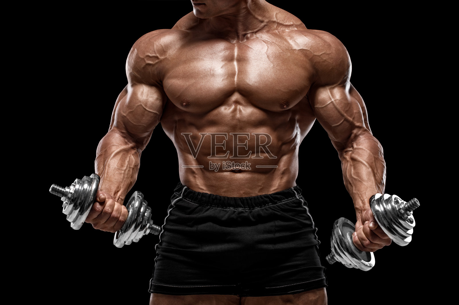 肌肉发达的人在锻炼，用哑铃做运动，在黑色背景下独处。强壮的男性裸体躯干腹肌照片摄影图片