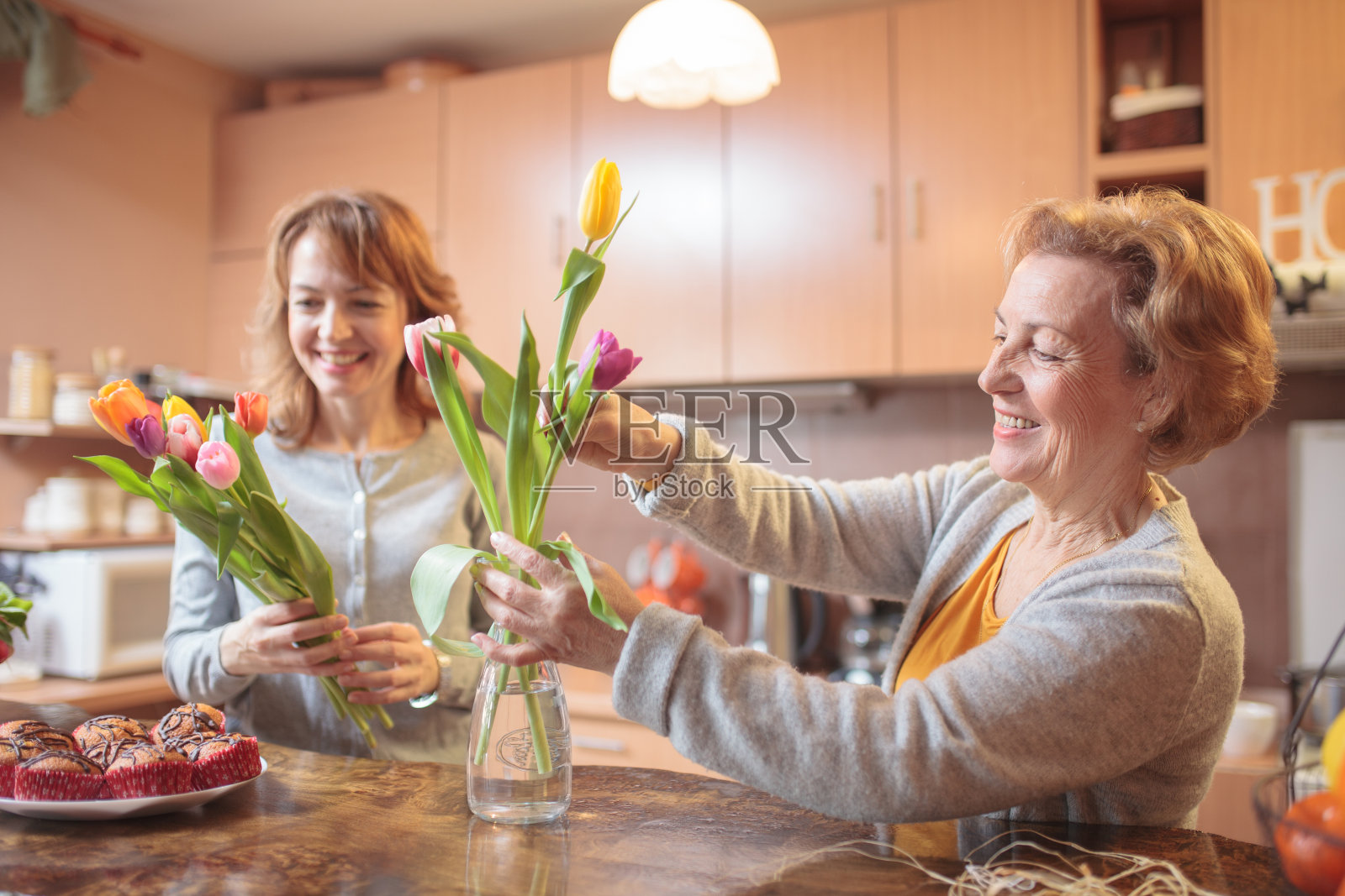 微笑快乐的资深白人妇女把郁金香放入花瓶照片摄影图片