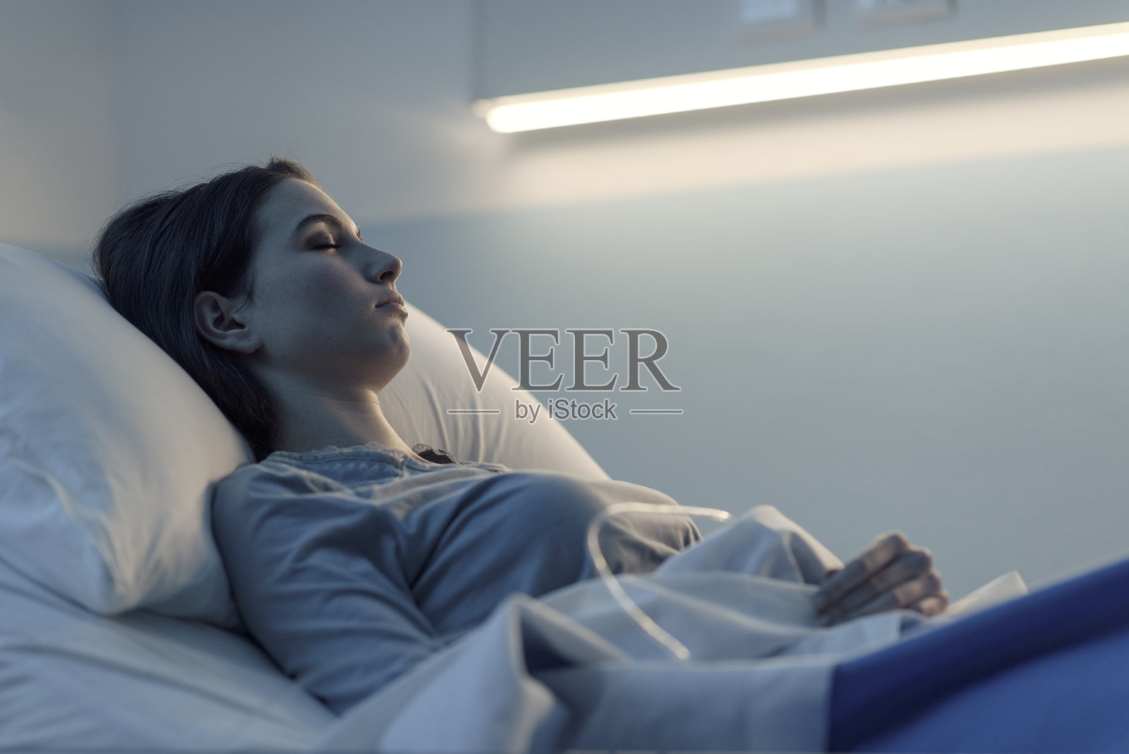 一个年轻女人晚上躺在医院的病床上照片摄影图片