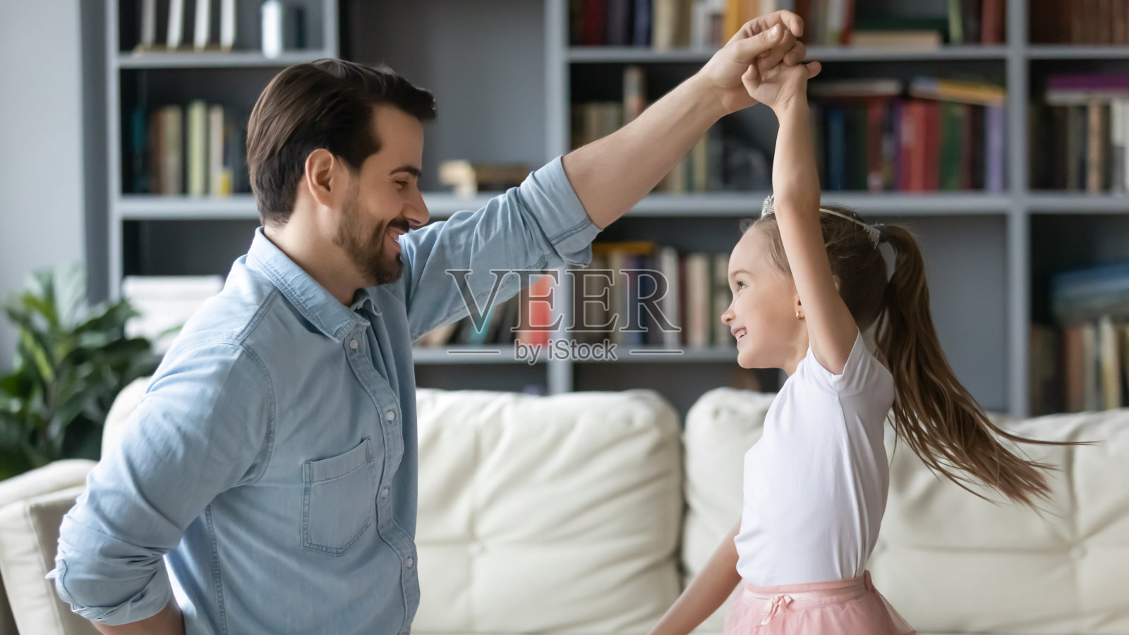年轻的父亲和兴奋的小女儿在家里跳舞照片摄影图片