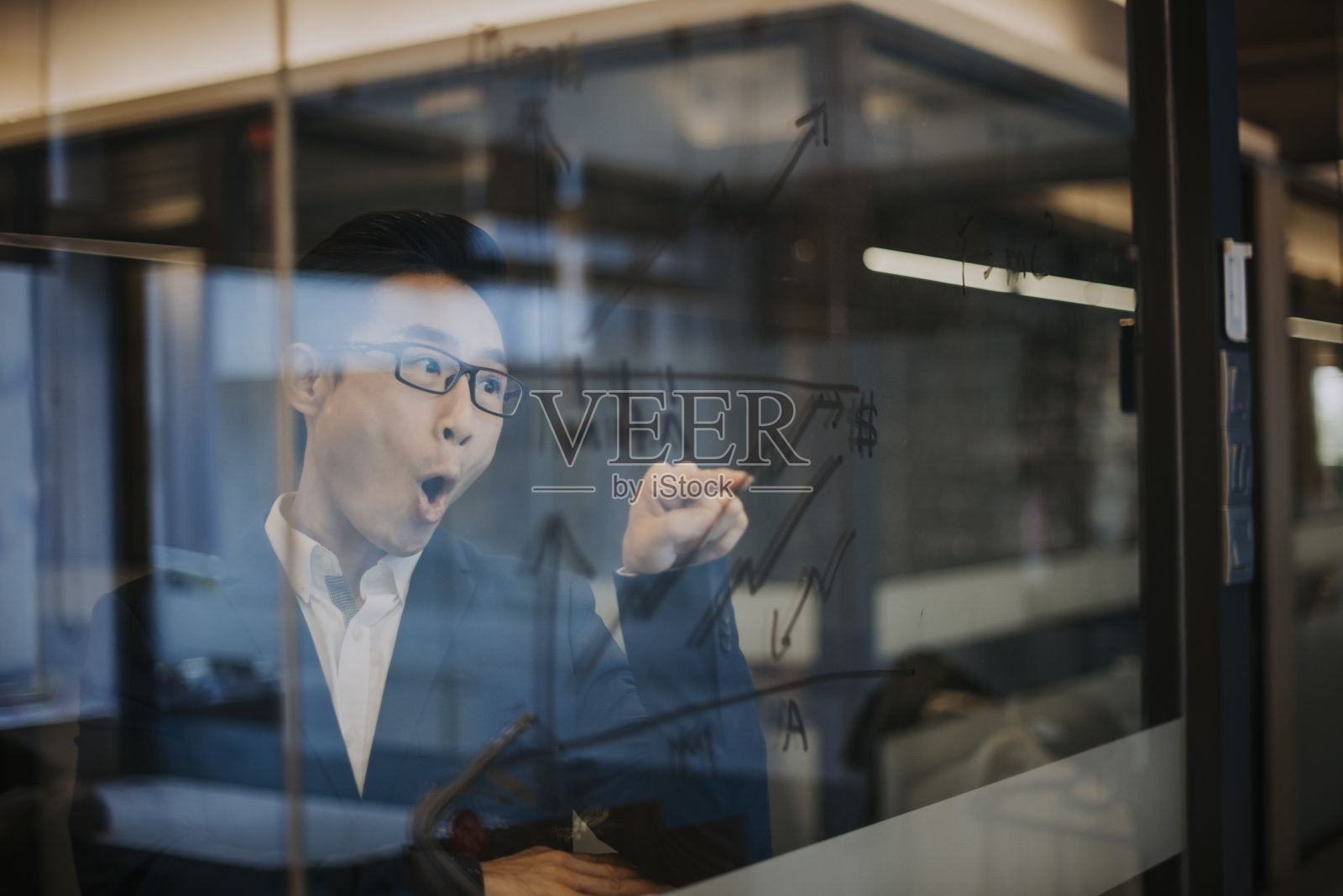 一个亚洲华人男性主管看着玻璃材料与所有的图表由马克笔照片摄影图片